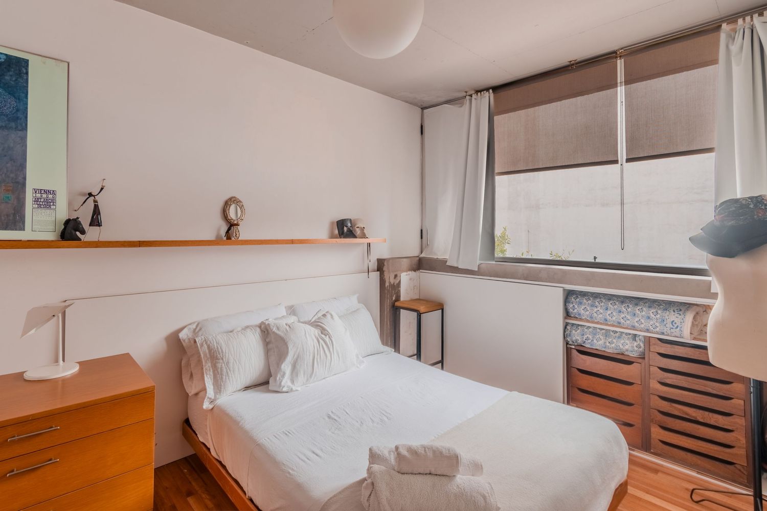 Fotografía de interior para inmobiliaria de dormitorio luminoso con cama doble y muebles de madera.