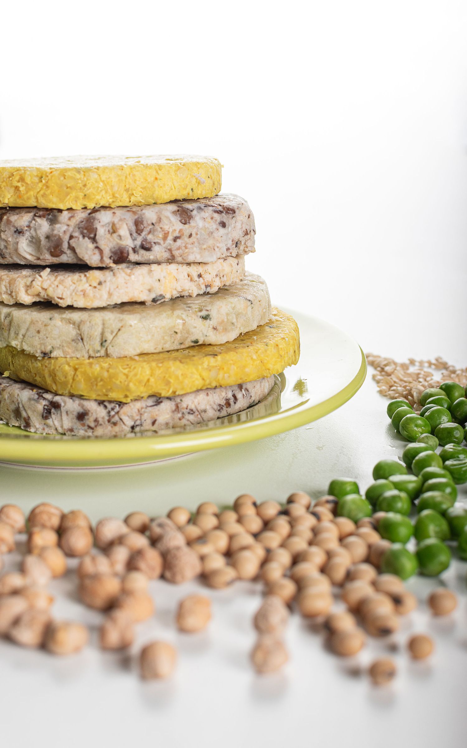 Fotografía de producto gastronómico para ecommerce de hamburguesas vegetales apiladas con granos y arvejas en escena de estudio.