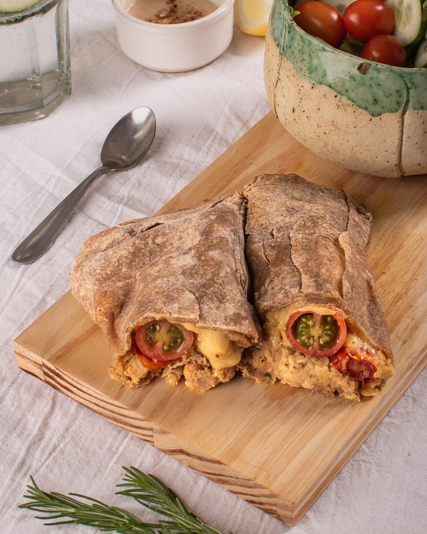 Fotografía gastronómica para ecommerce de wrap relleno en tabla de madera con ambientación de alimentos.
