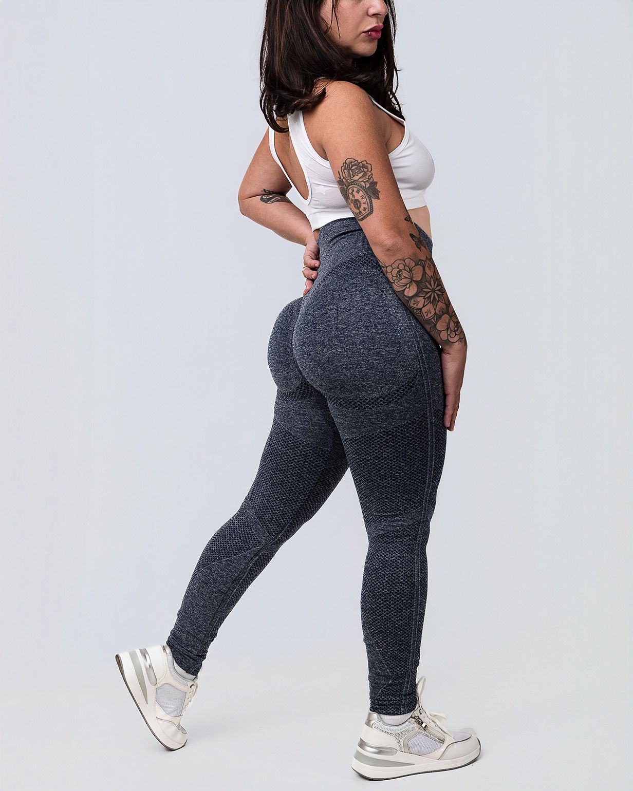 Fotografía e-commerce de indumentaria deportiva femenina con calza gris jaspeada en vista lateral sobre fondo neutro.