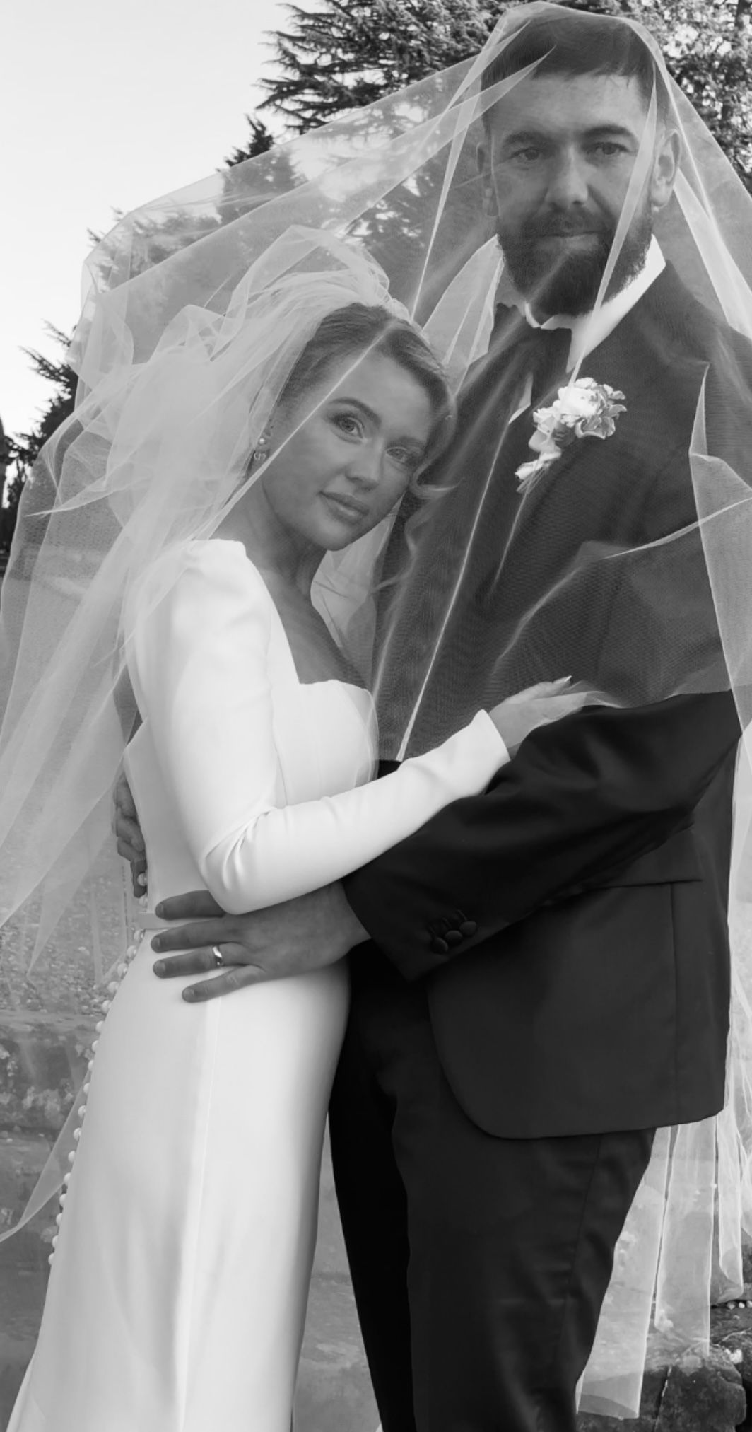 Romantic black and white wedding portraits under a flowing veil outdoors.