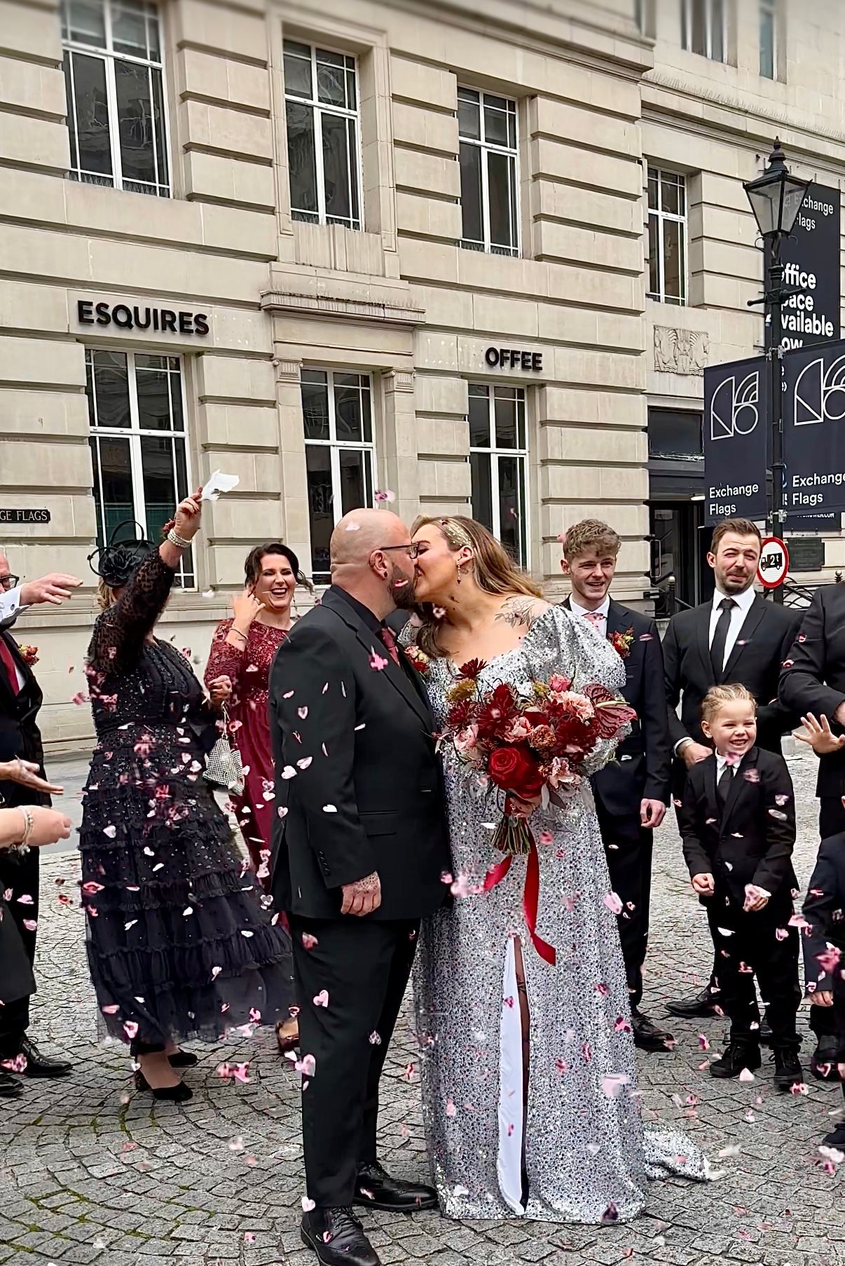 Wedding celebration outside a historic building with guests throwing confetti at the newlyweds. wedding content
