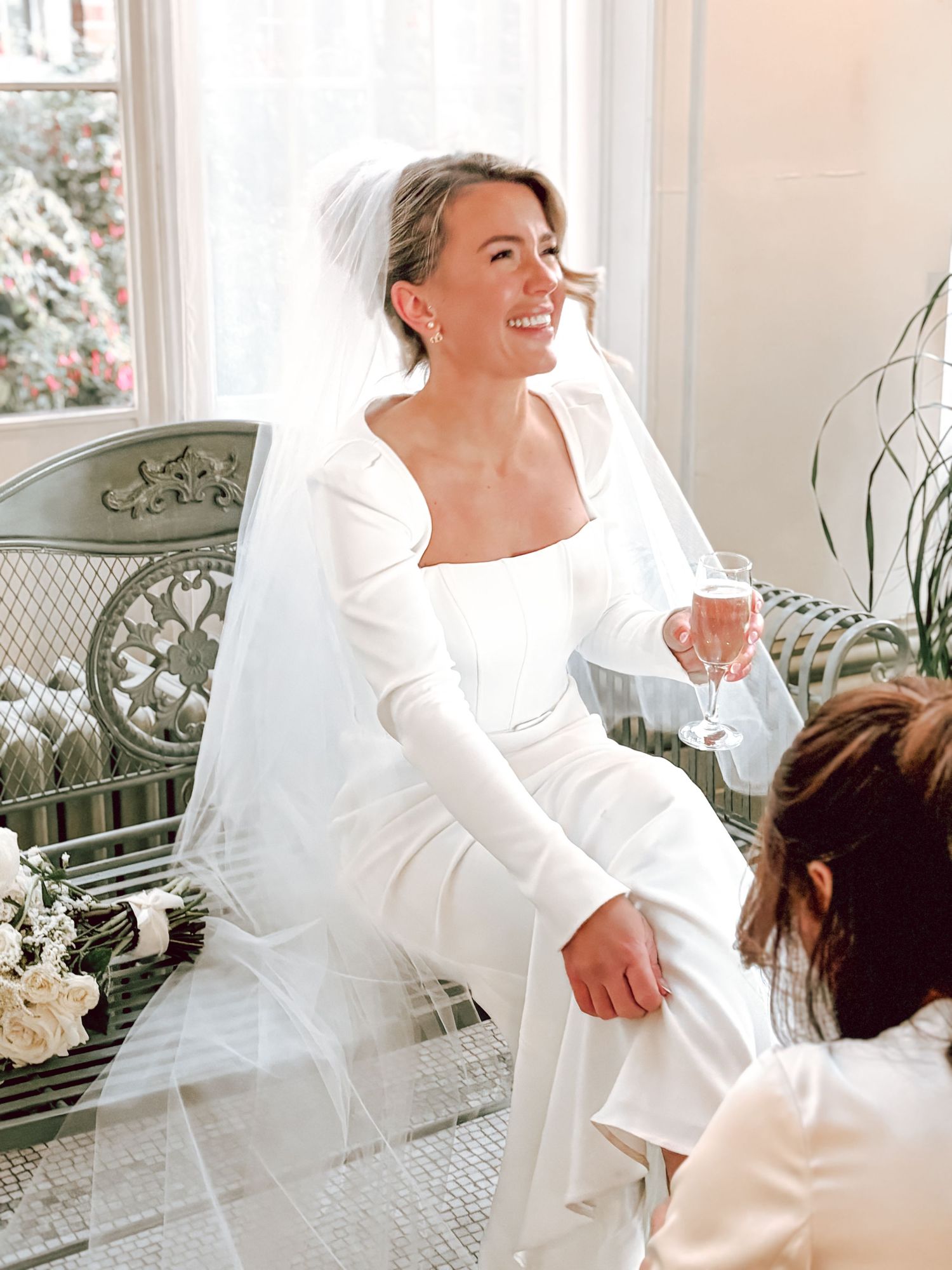 Elegant bridal portraits by a window showing natural laughing moments.