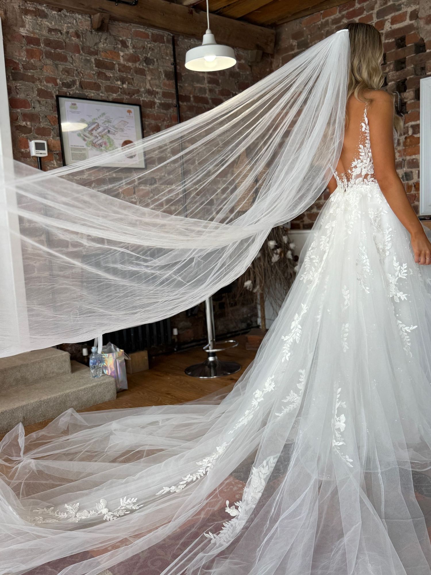 Dramatic cathedral length veil and train of white wedding gown in rustic brick venue.