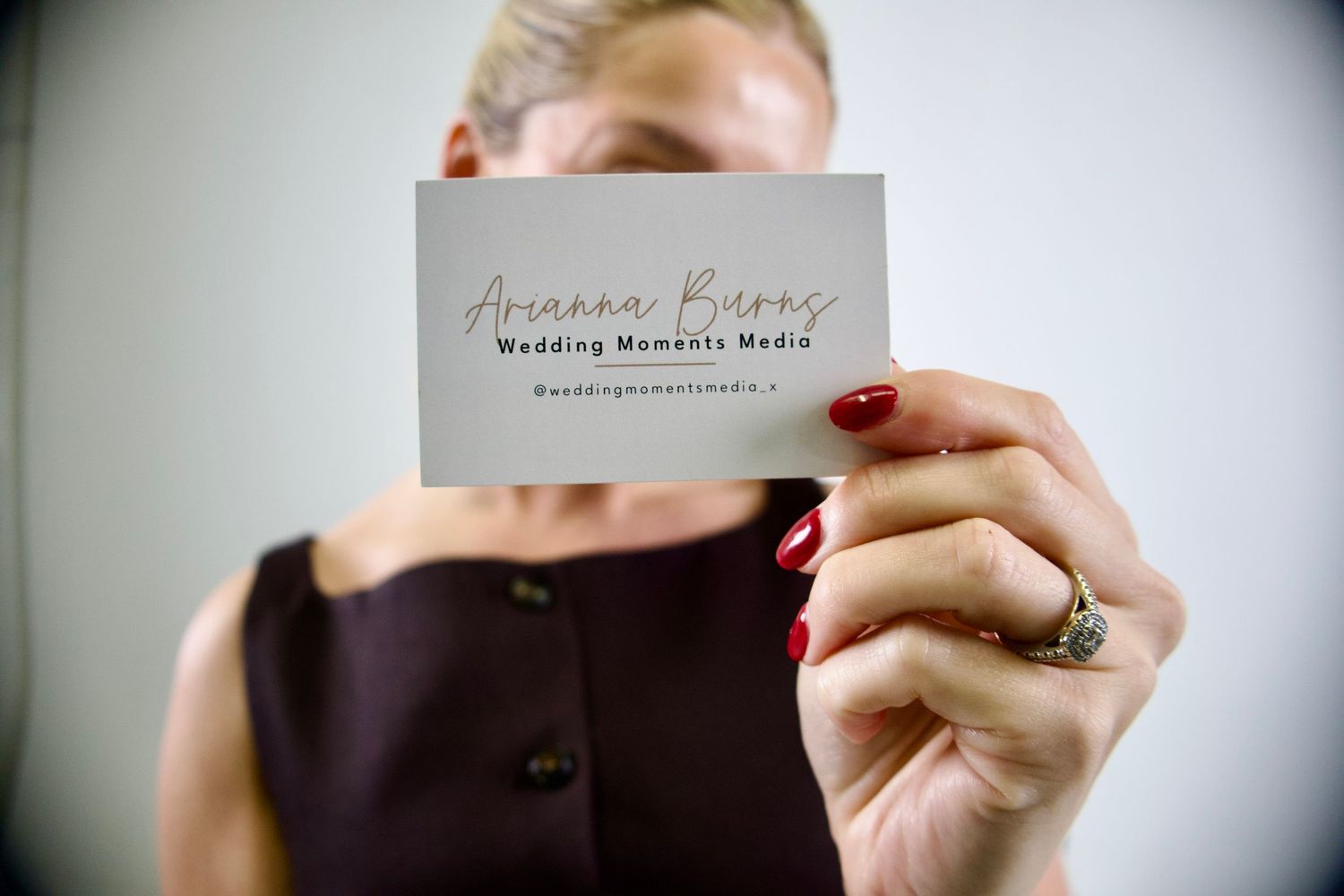 Close-up of hands holding an elegant wedding photographer's business card.