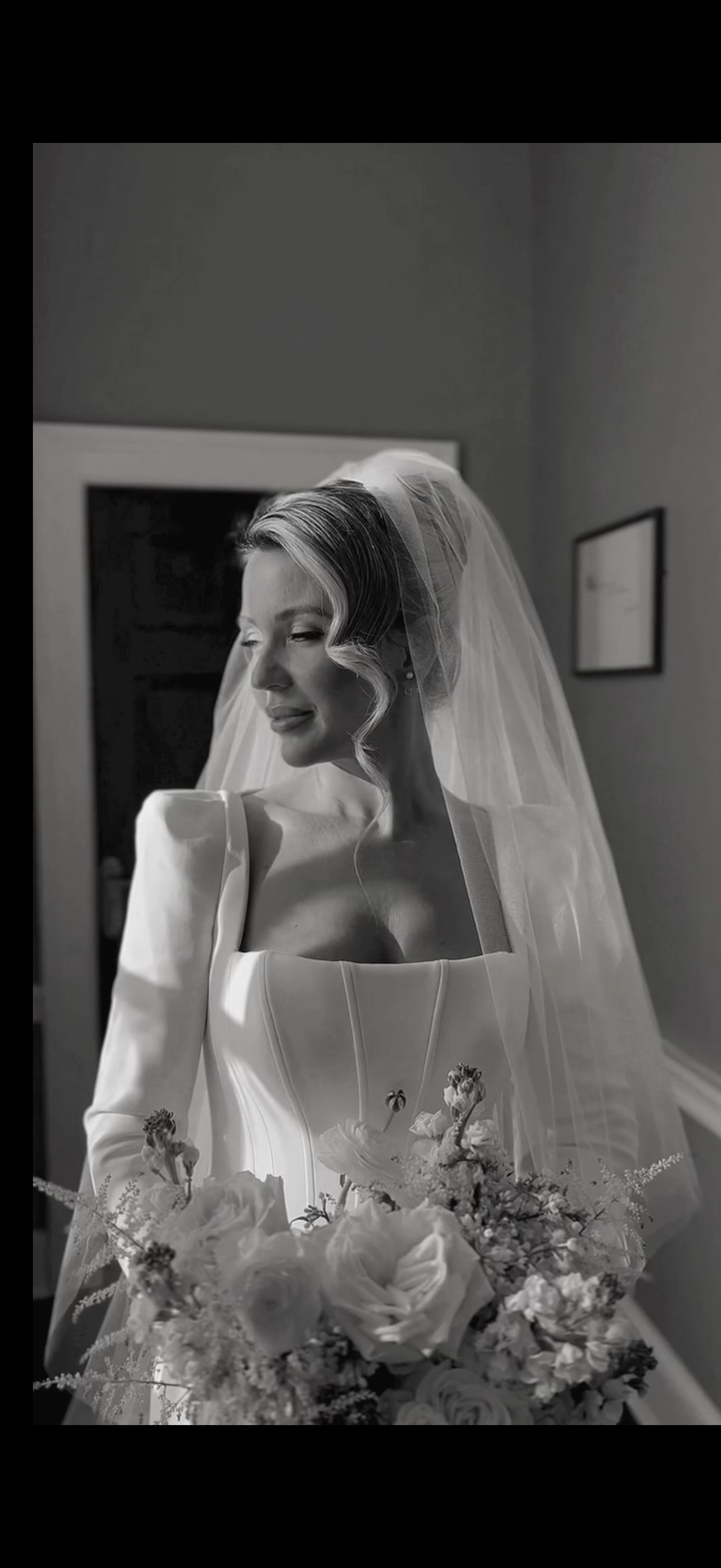 Black and white bridal portrait featuring elegant wedding dress and floral bouquet.