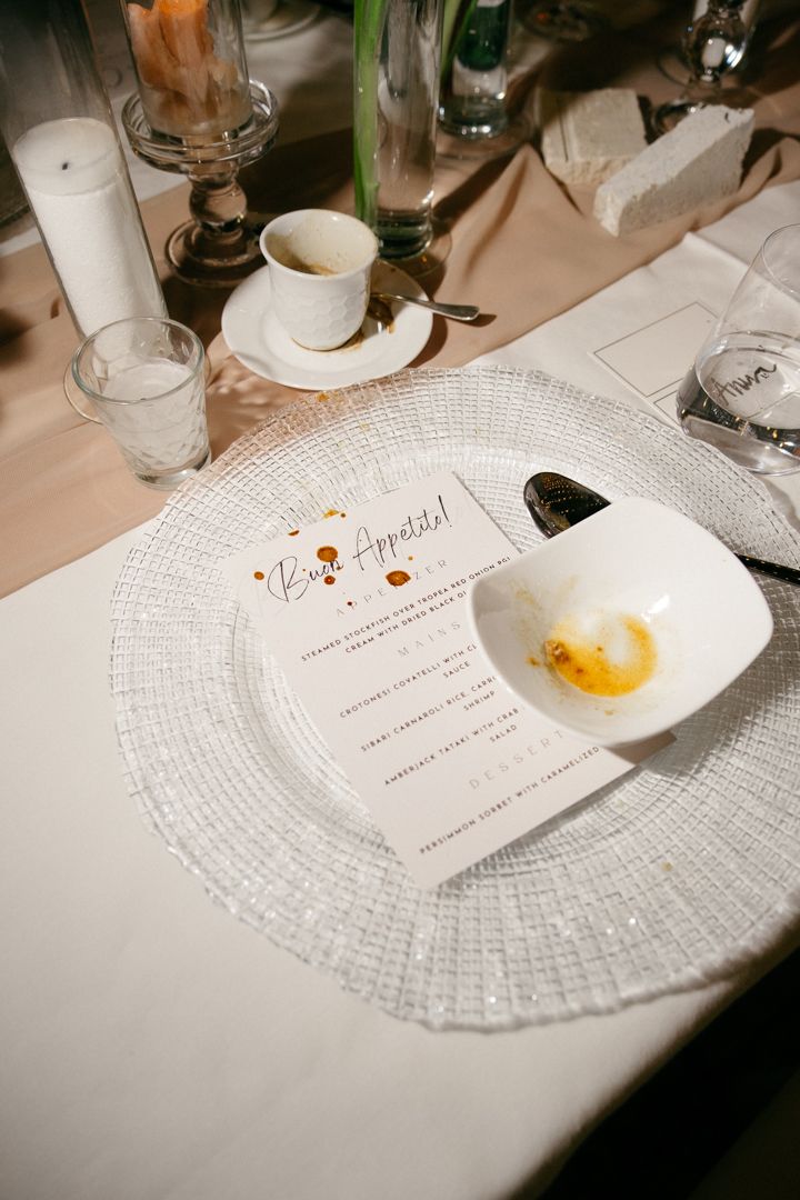 A series of white plates with menus and food remnants arranged on a dining table during an elegant meal service.