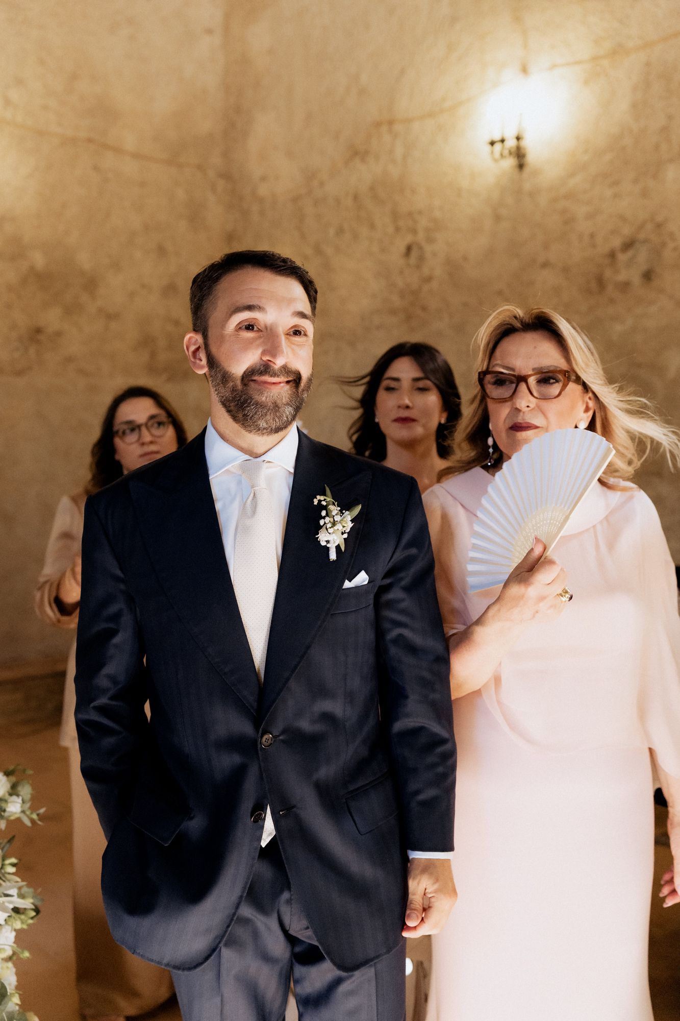 Wedding guests and attendees gathered in a rustic stone-walled room during ceremony.