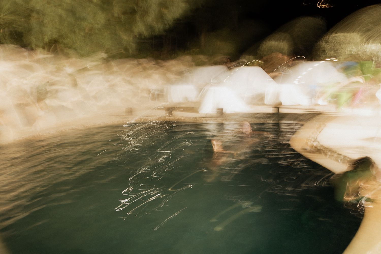 Artistic blurred photograph of a natural water feature or pool with warm tones.