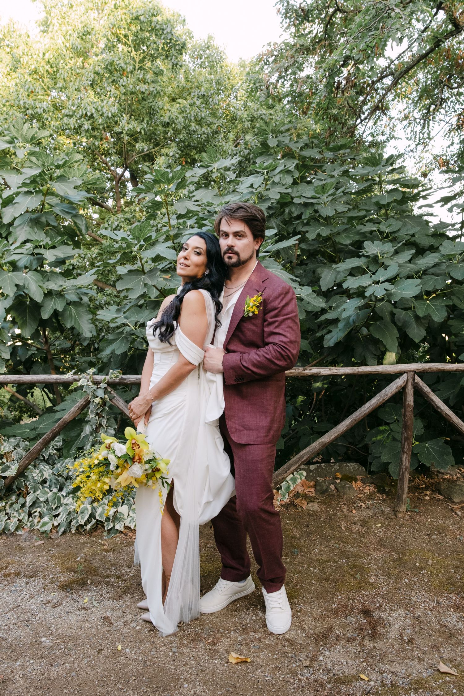 Wedding couple shares intimate moment against garden backdrop.