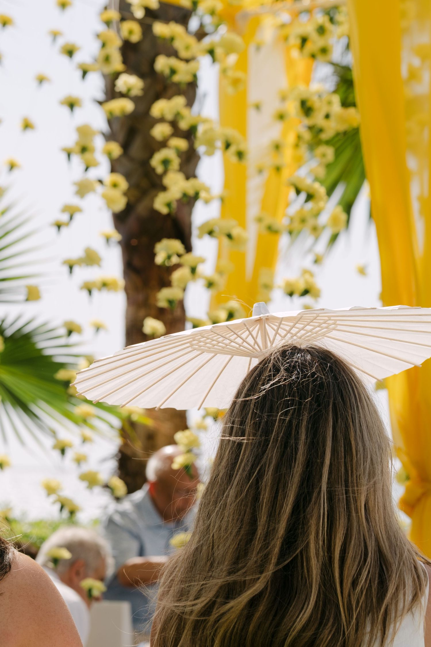 White paper parasols create an elegant decorative canopy against a golden yellow backdrop with twinkling lights.