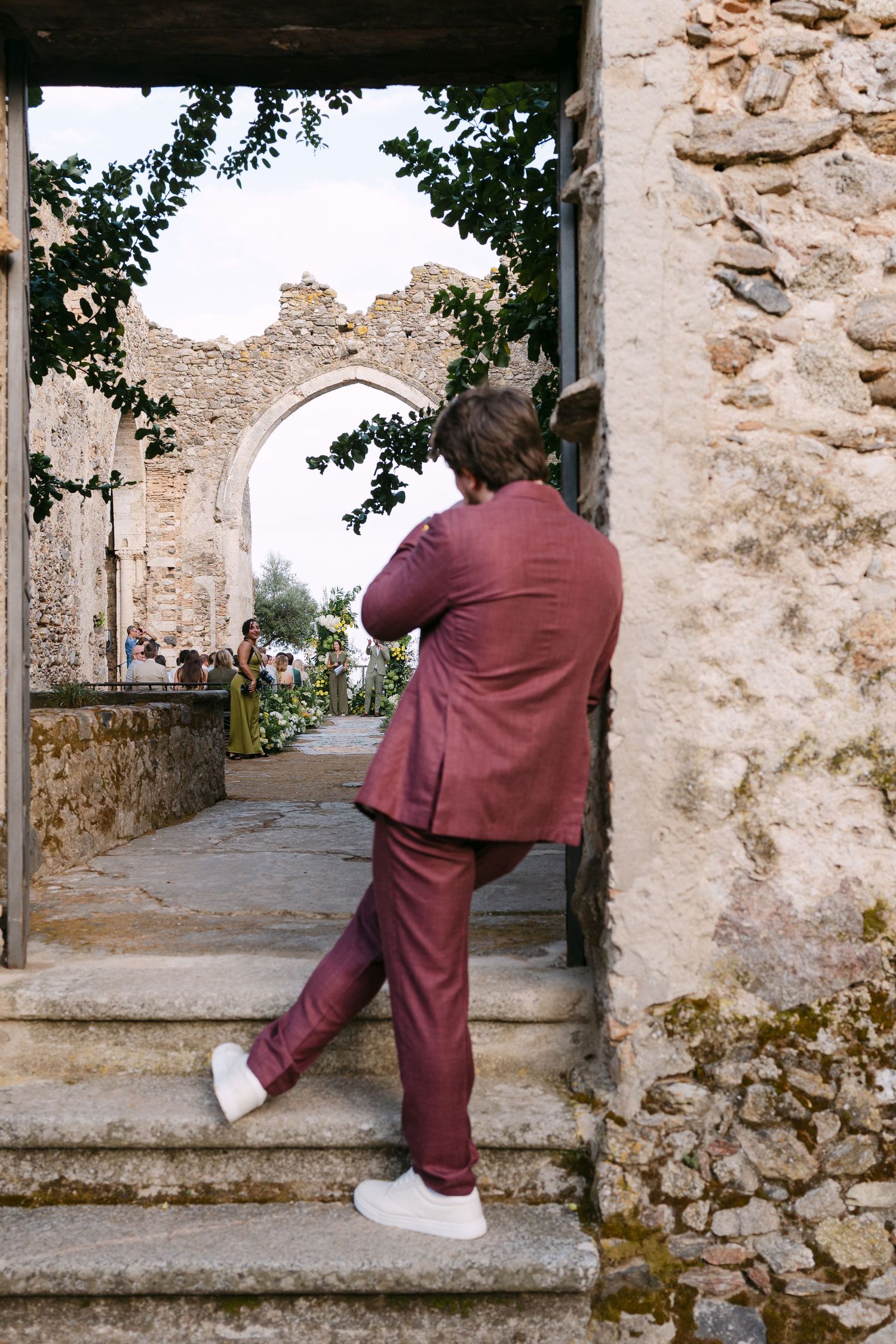 Someone in burgundy attire climbs stone steps within historic ruins.