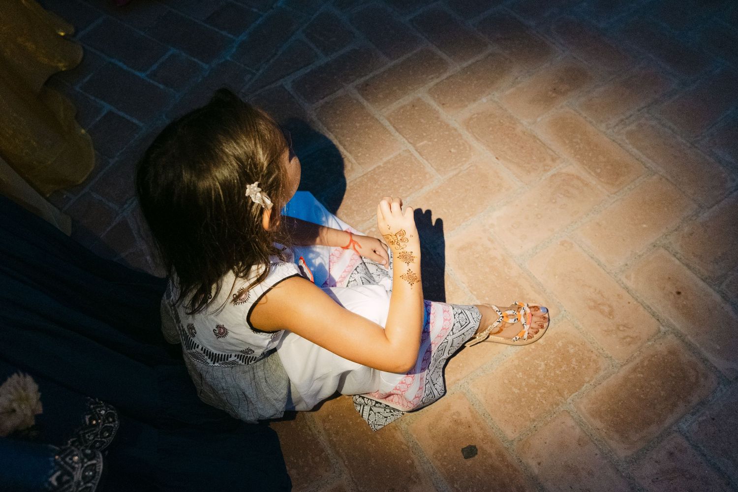 A child draws with chalk on a stone floor in dim lighting conditions.