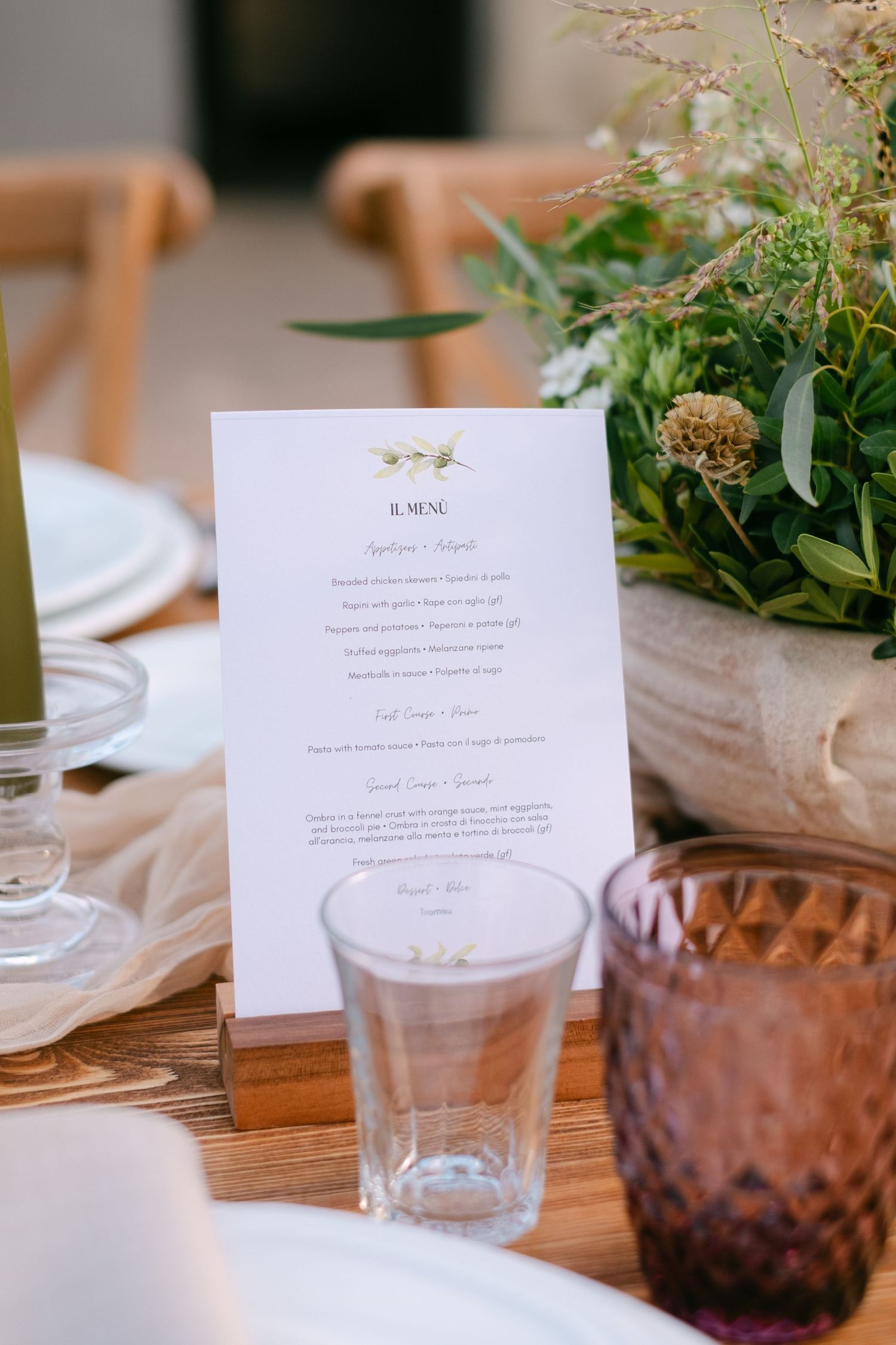 Wedding reception table settings with menu cards and purple glassware alongside delicate floral arrangements.