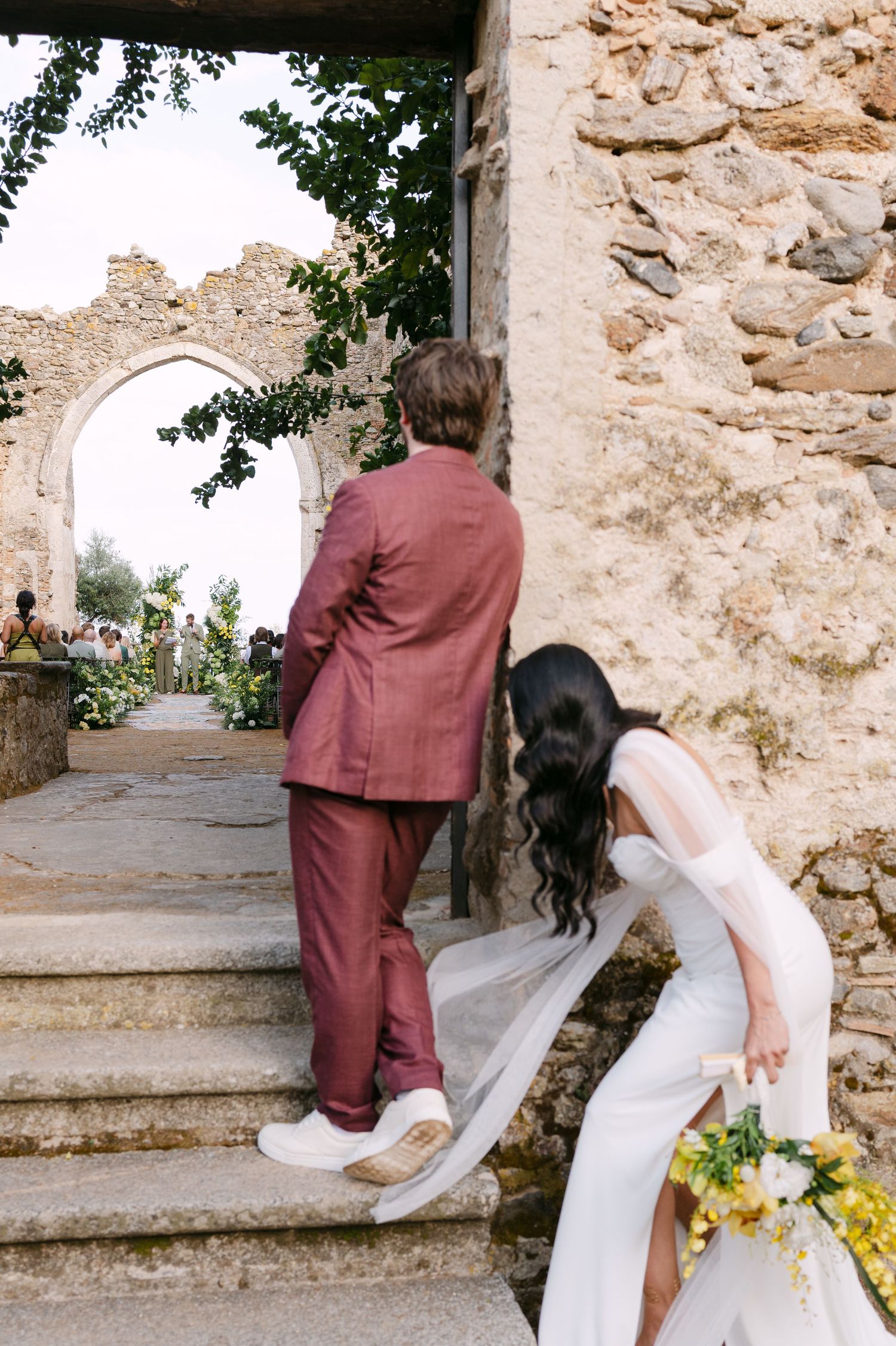 A couple ascends stone steps during their wedding celebration.
