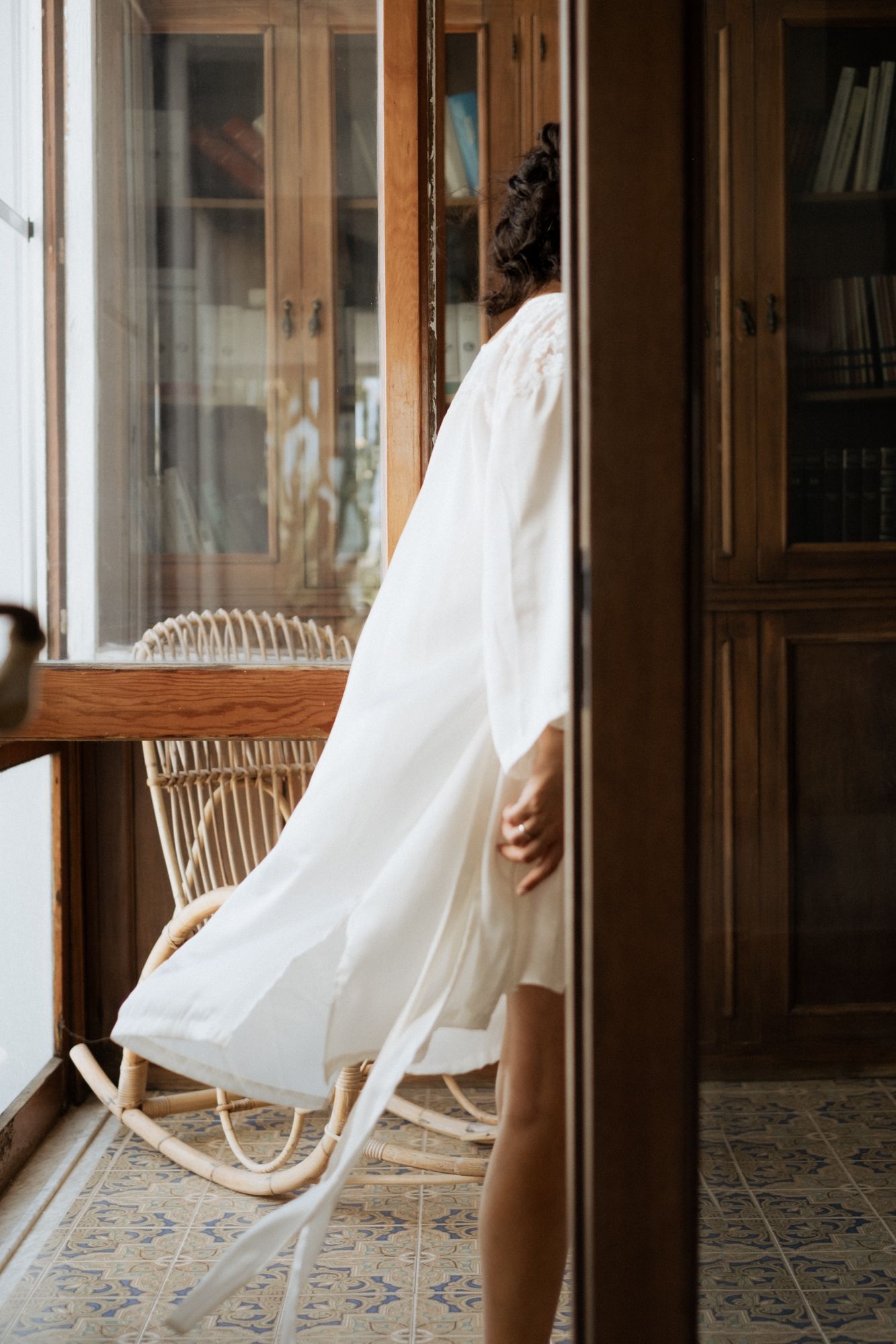 Flowing white fabric movement captured in sequence against interior setting with rattan chair.