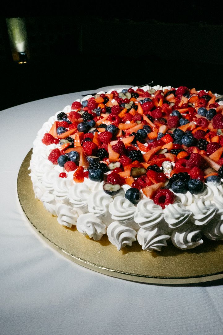 A delectable pavlova topped with fresh mixed berries and whipped cream swirls arranged in a circular pattern.