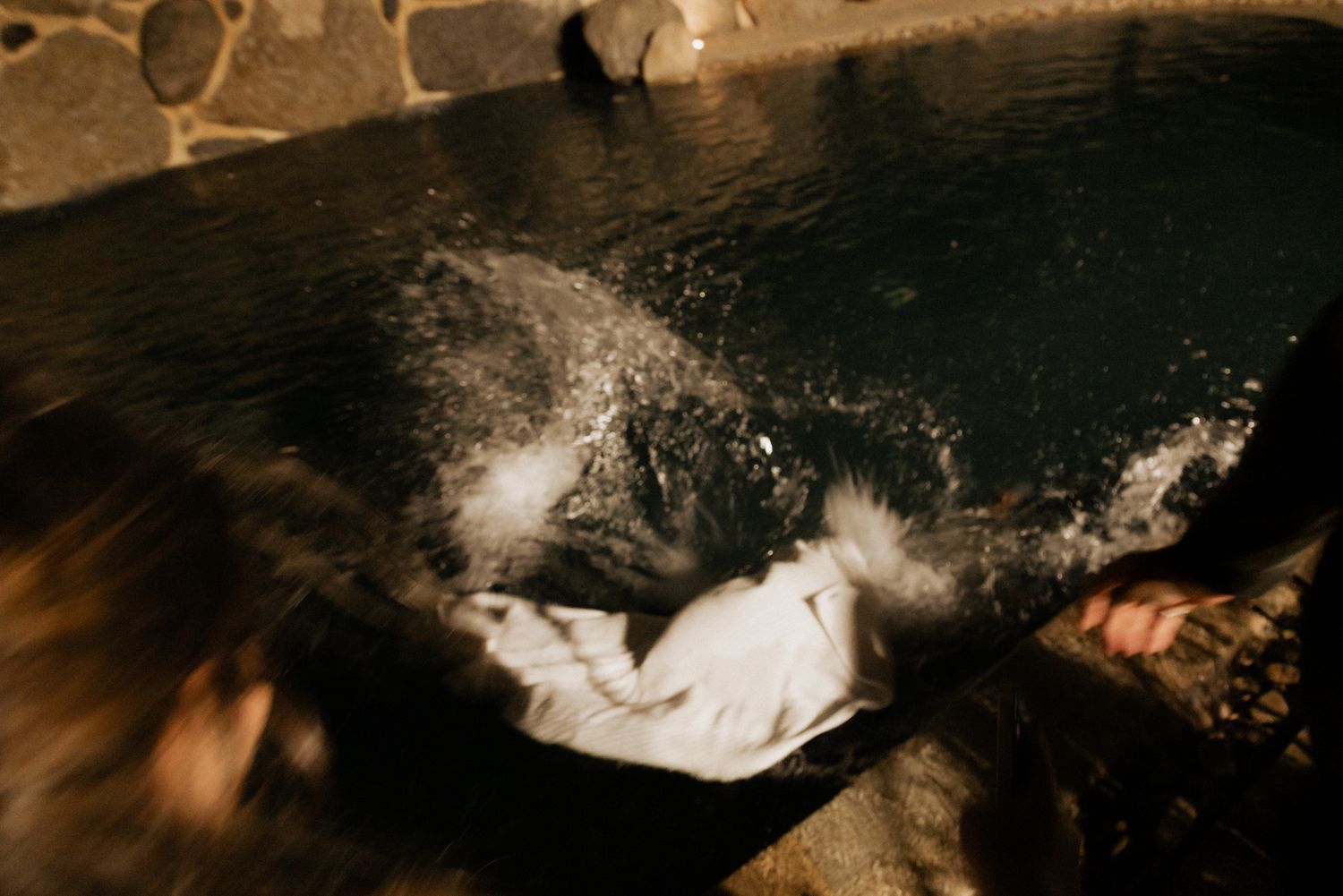 Artistic underwater shot of flowing white fabric in dark pool.