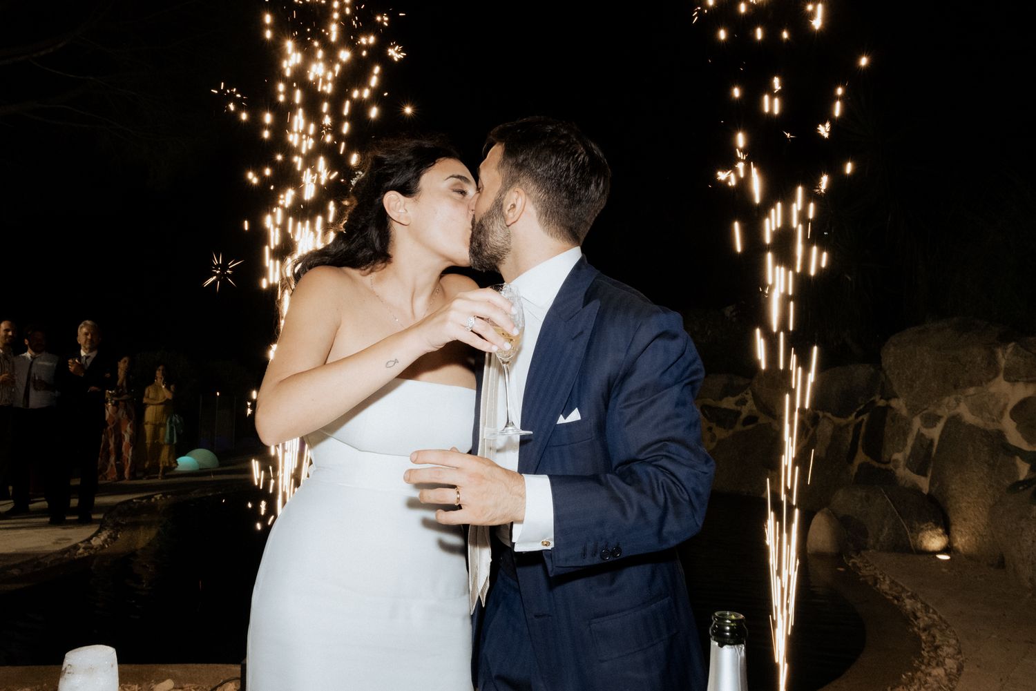 Wedding couple dancing with sparkler effects creating dramatic lighting in dark setting.
