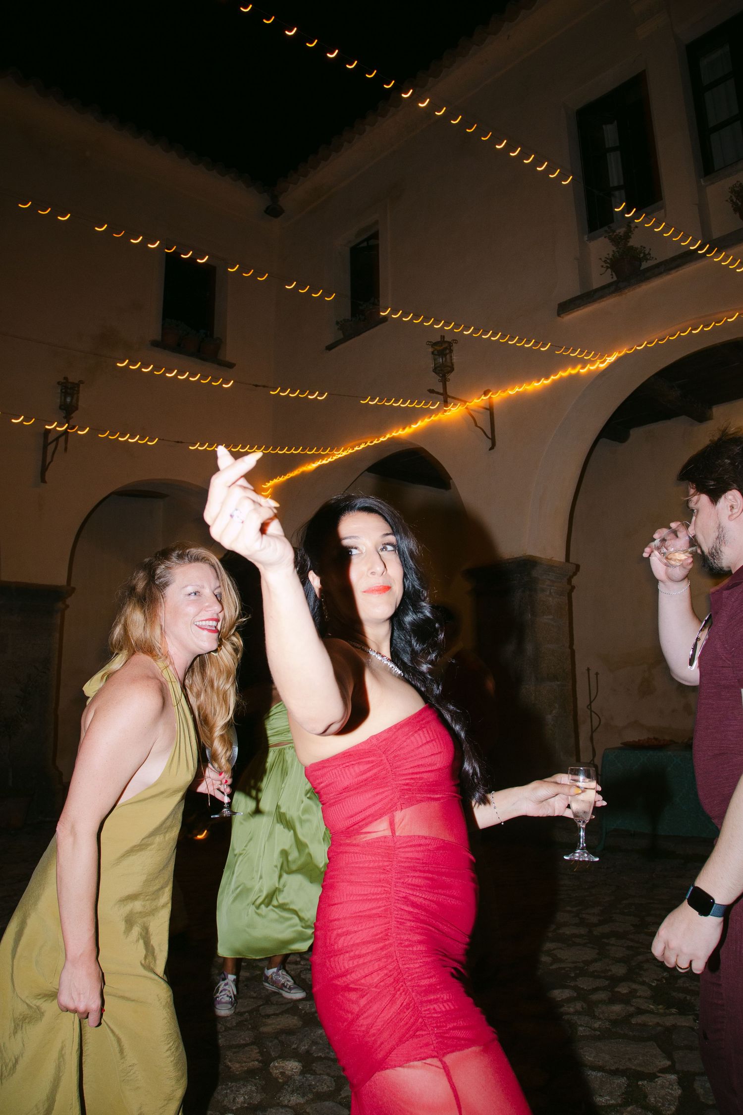 People dancing under string lights at a nighttime wedding reception.