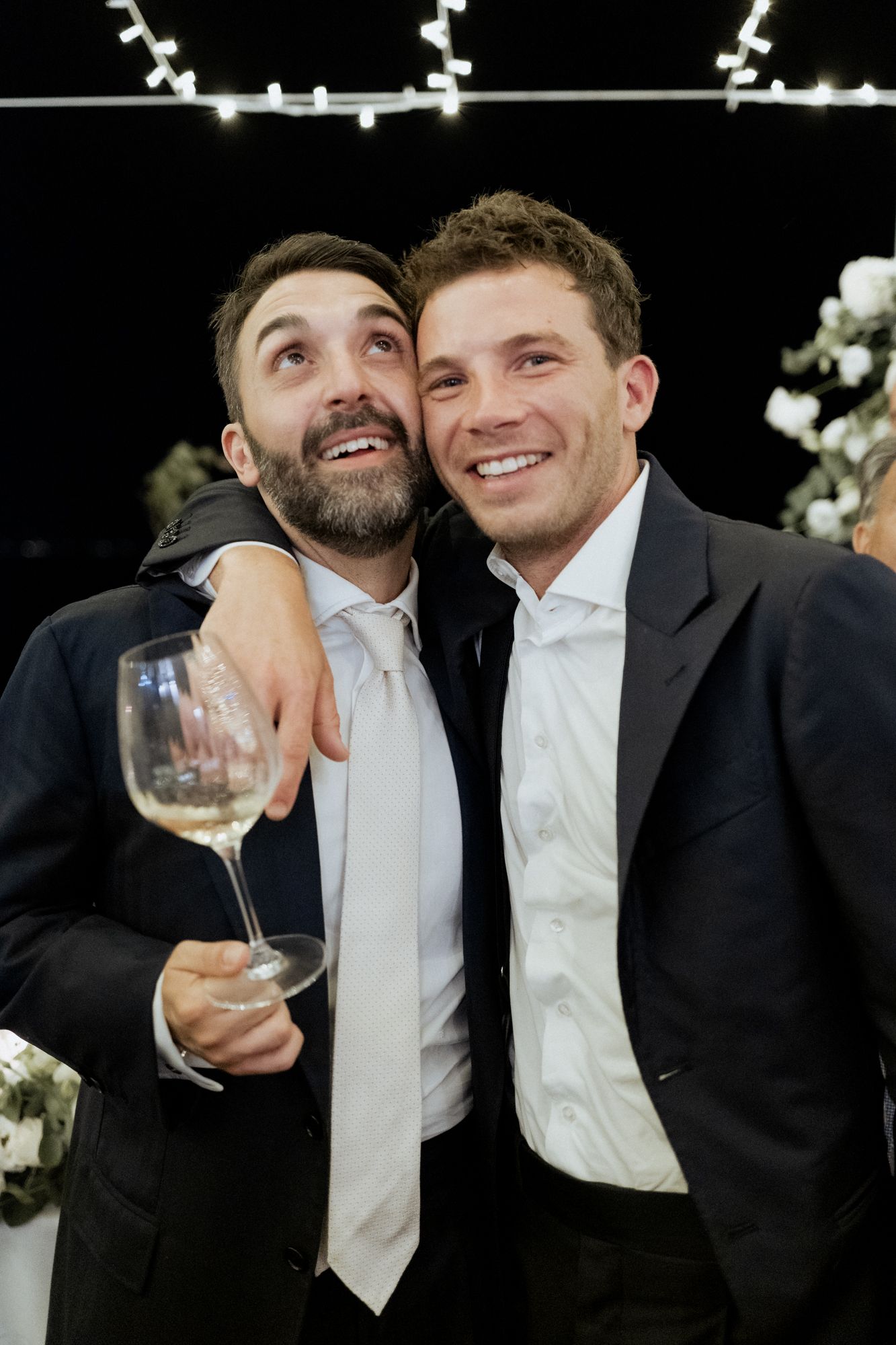 Groomsmen in formal attire share a lighthearted moment at the wedding reception.