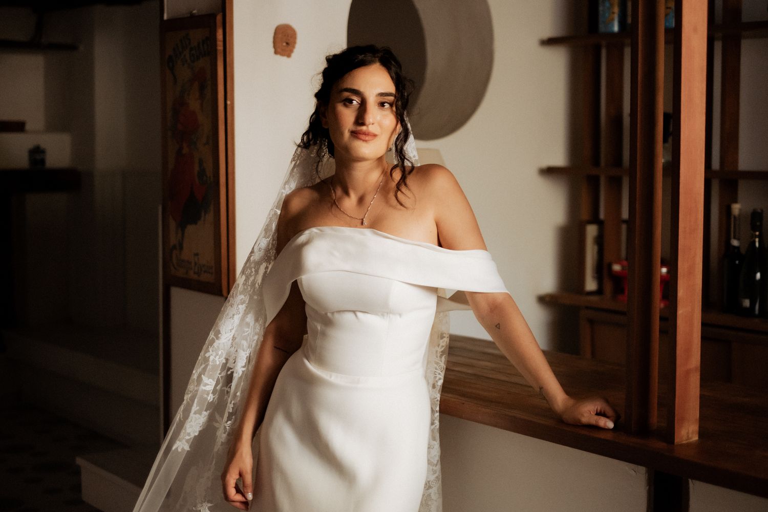 A bride poses in an elegant strapless wedding dress against a wooden paneled wall.