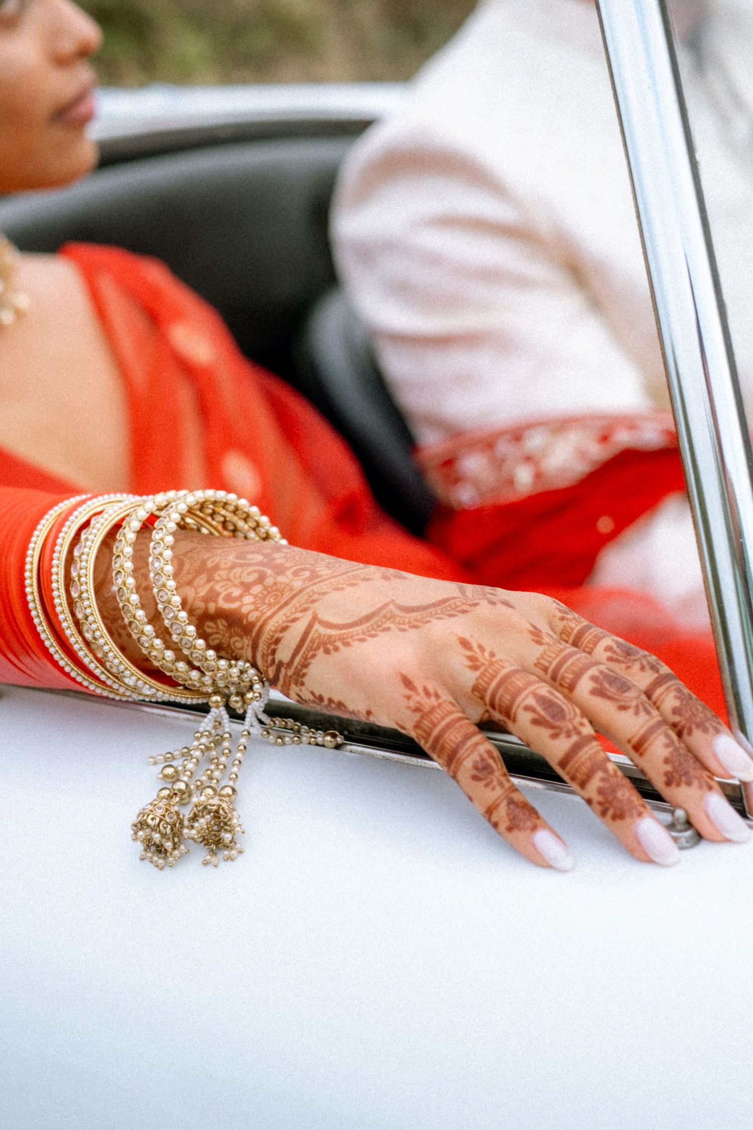 Hands adorned with intricate henna designs and gold bangles display traditional Indian bridal jewelry.