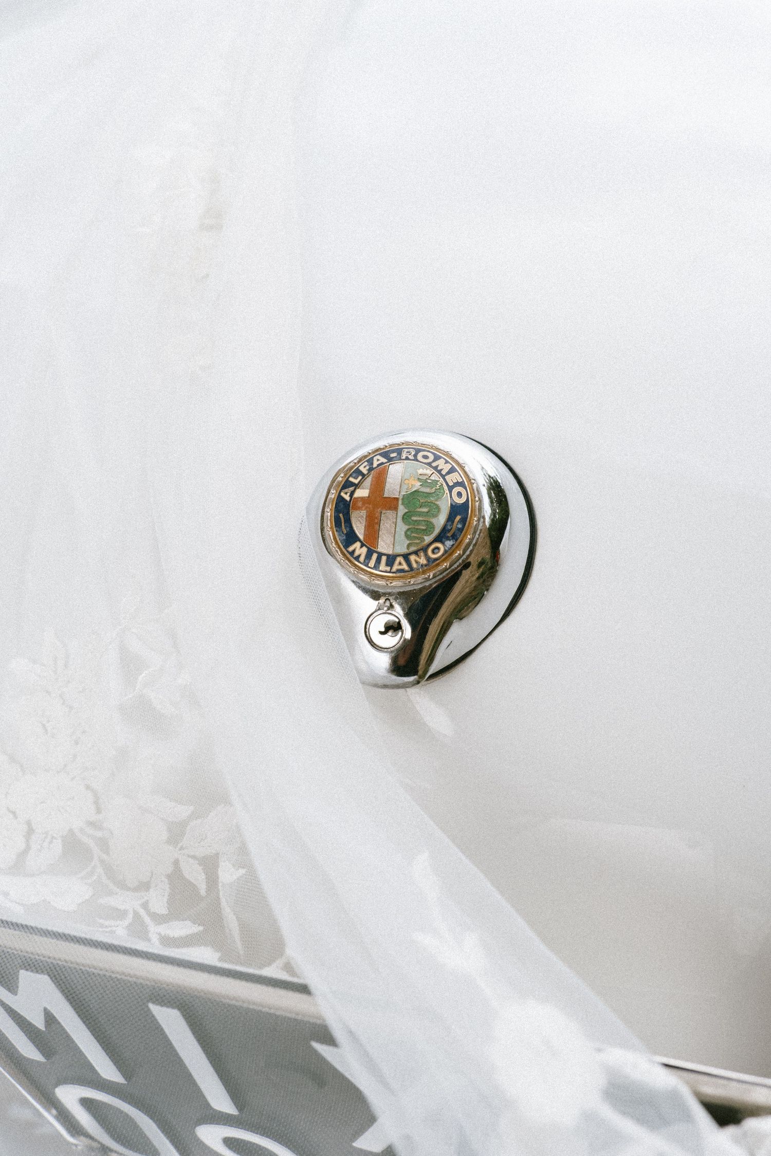 Wedding rings and jewelry details arranged artistically on white fabric.