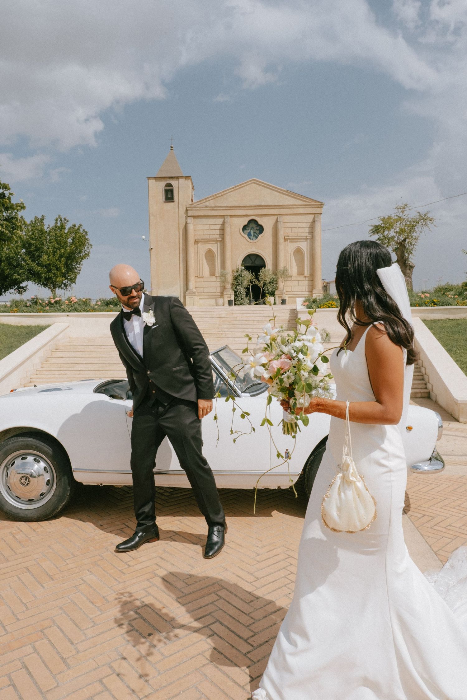 A playful wedding couple poses for creative photos in front of a historic church building.