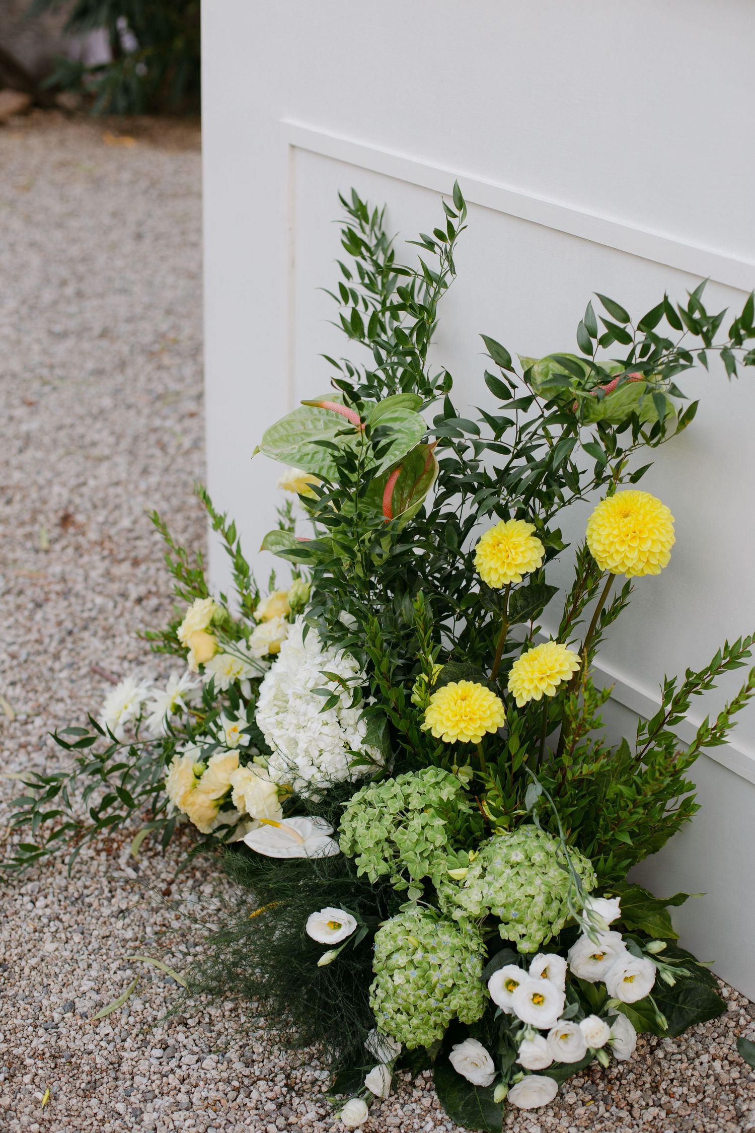Fresh floral arrangement featuring yellow dahlias, white hydrangeas and green foliage.
