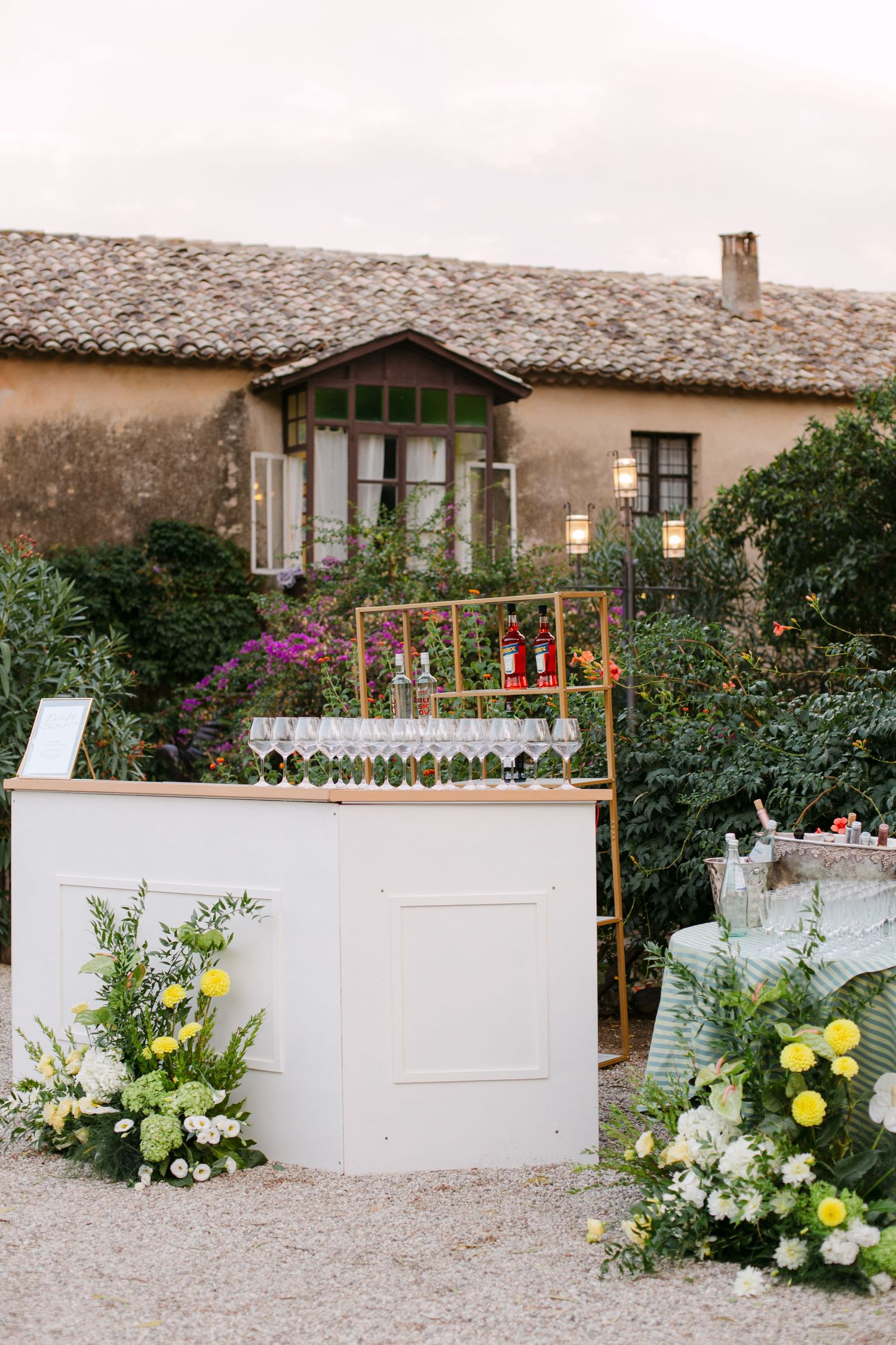 White decorative walls adorned with yellow and white floral arrangements at outdoor venue.