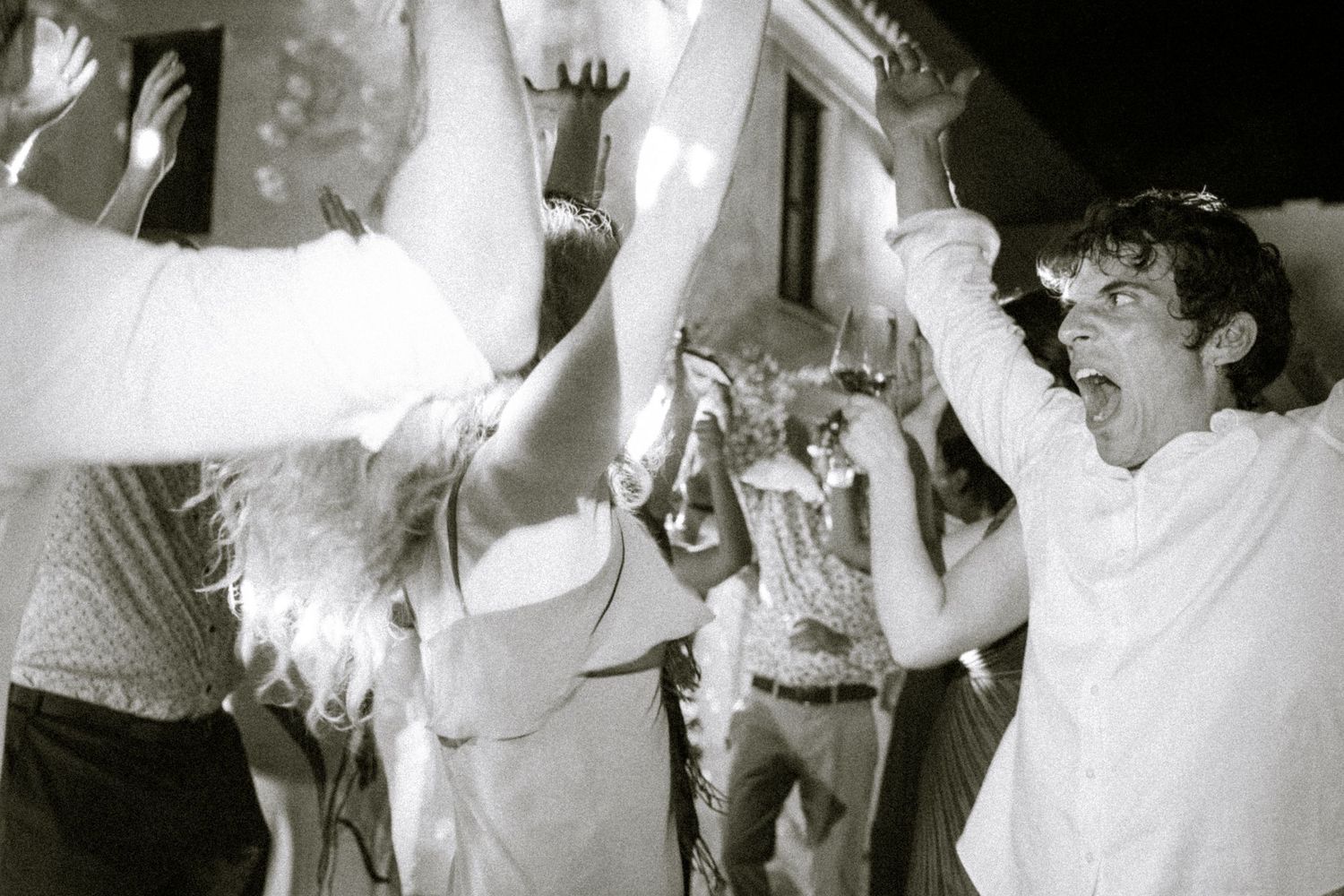 Black and white photo of wedding guests dancing and celebrating on dance floor.