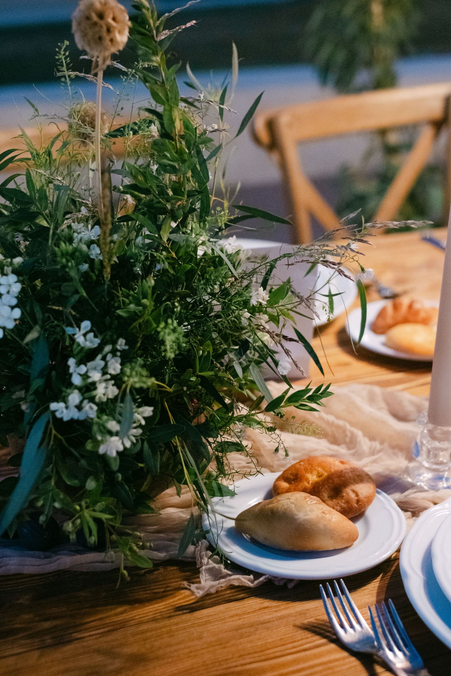 Rustic wedding table settings with greenery centerpieces and place settings on wooden tables.