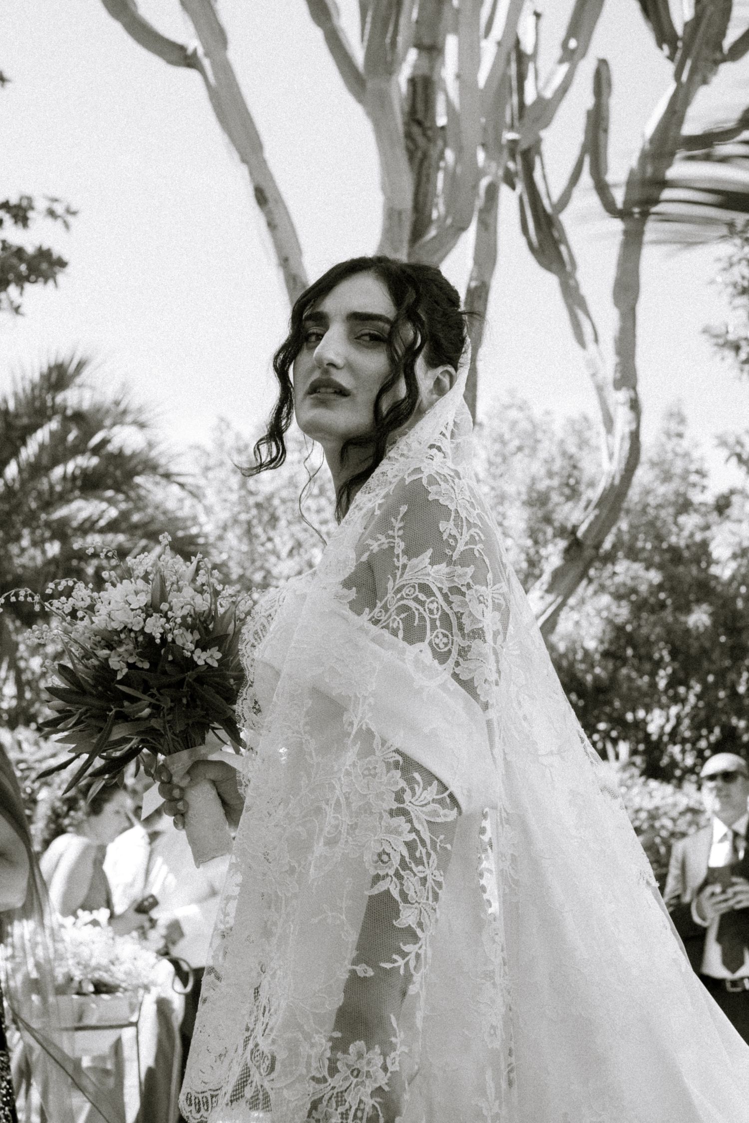 A black and white artistic photo series showing someone wearing a flowing ethereal white dress outdoors among trees.