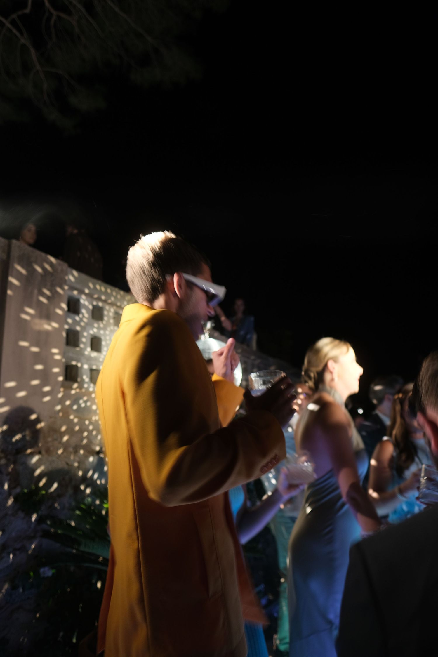 Black and white photograph of wedding reception dance party under palm trees.