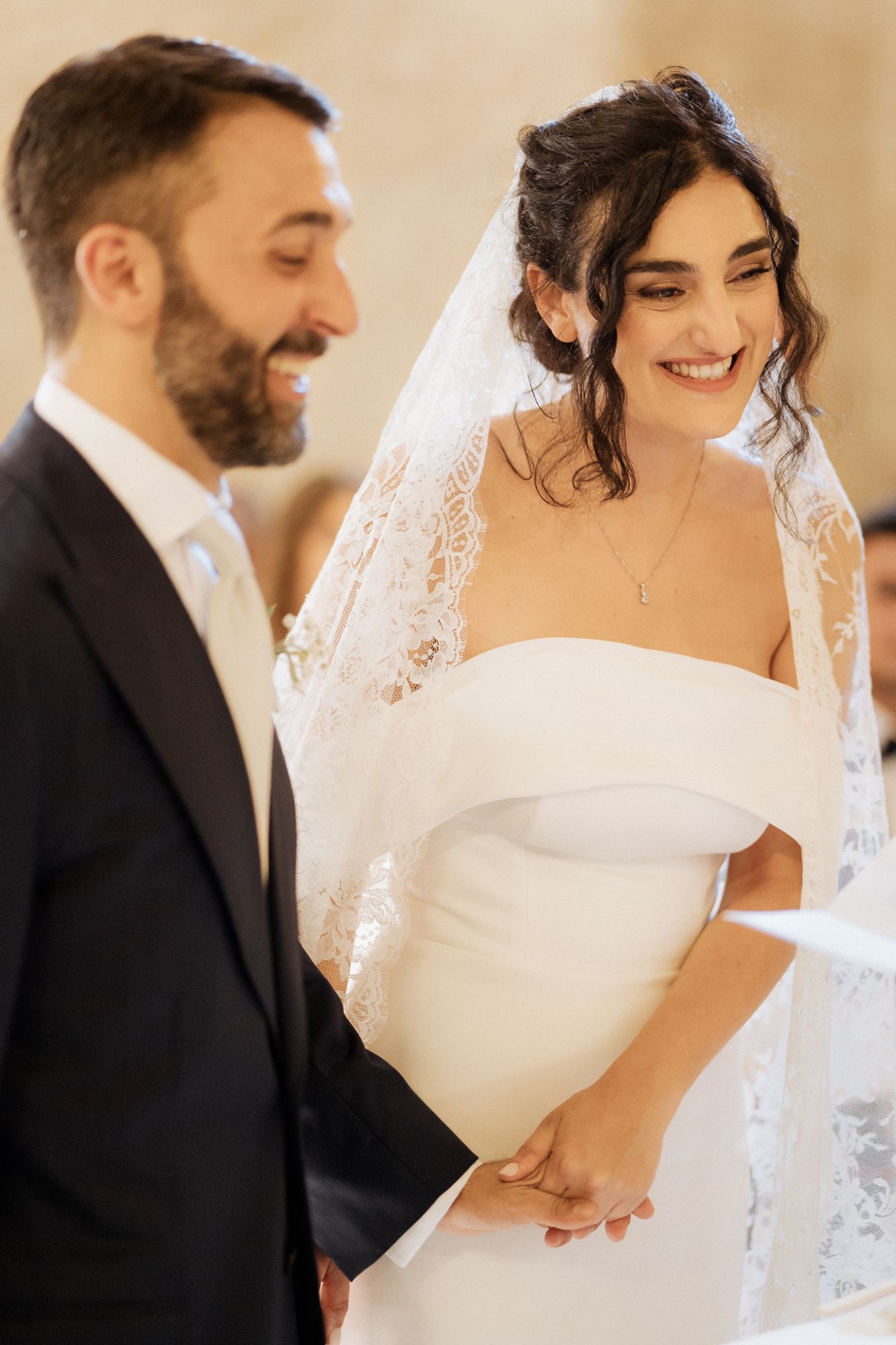 A tender wedding moment between a couple in elegant attire with the bride wearing a stunning white gown and veil.