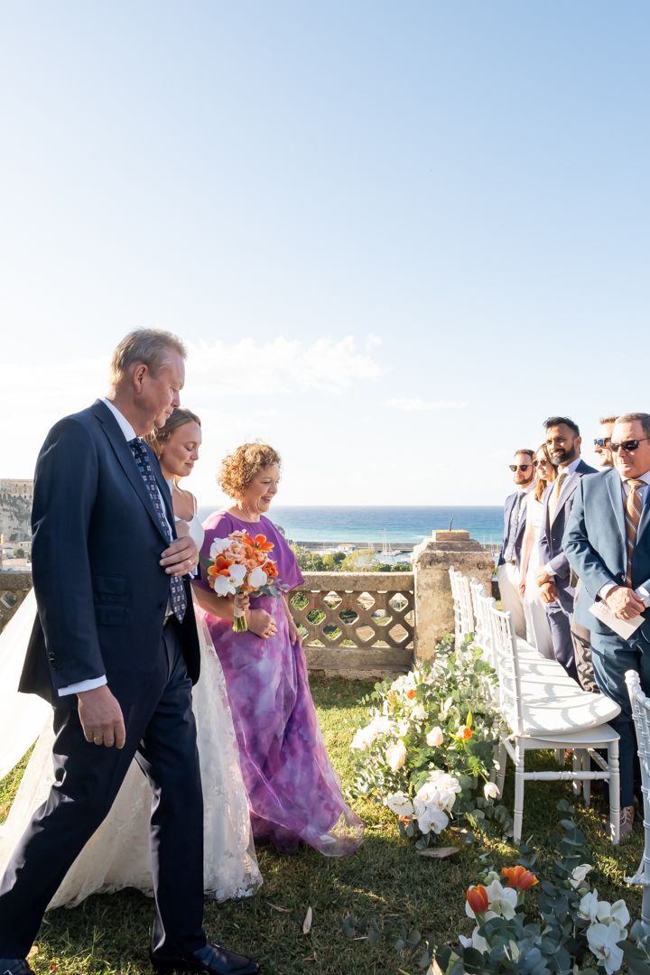 Wedding guests mingle on a scenic outdoor terrace overlooking the ocean.