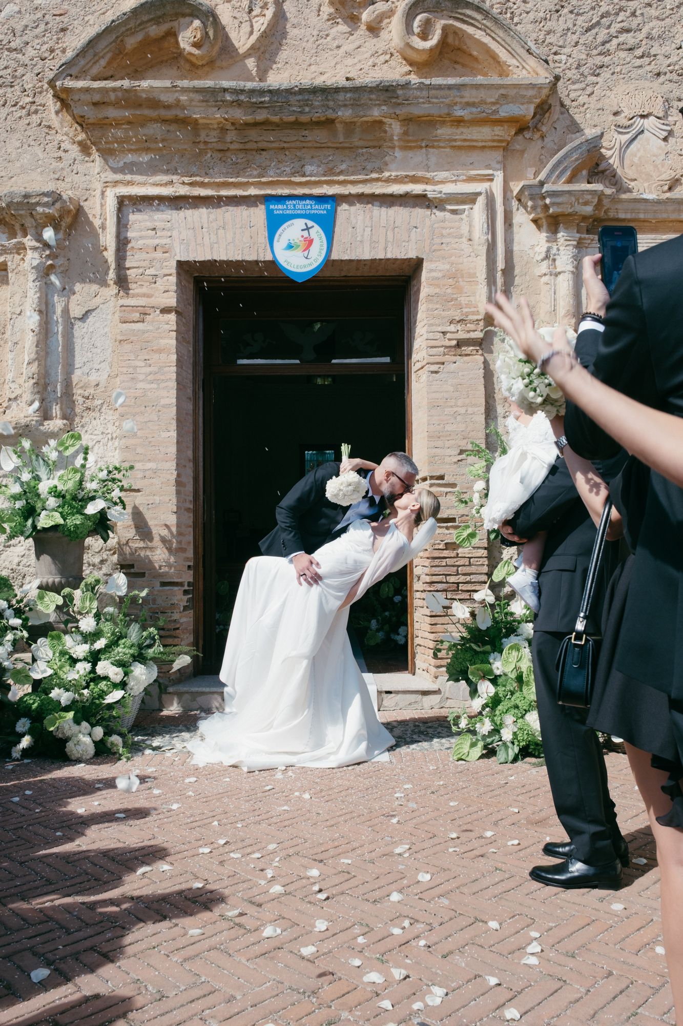 Wedding celebration captured in sequence outside historic brick building with floral decorations.