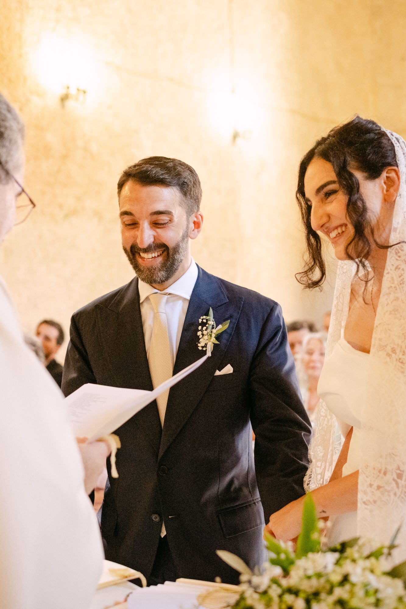 Joyful wedding ceremony moment showing couple and guests sharing laughter during an intimate indoor celebration.