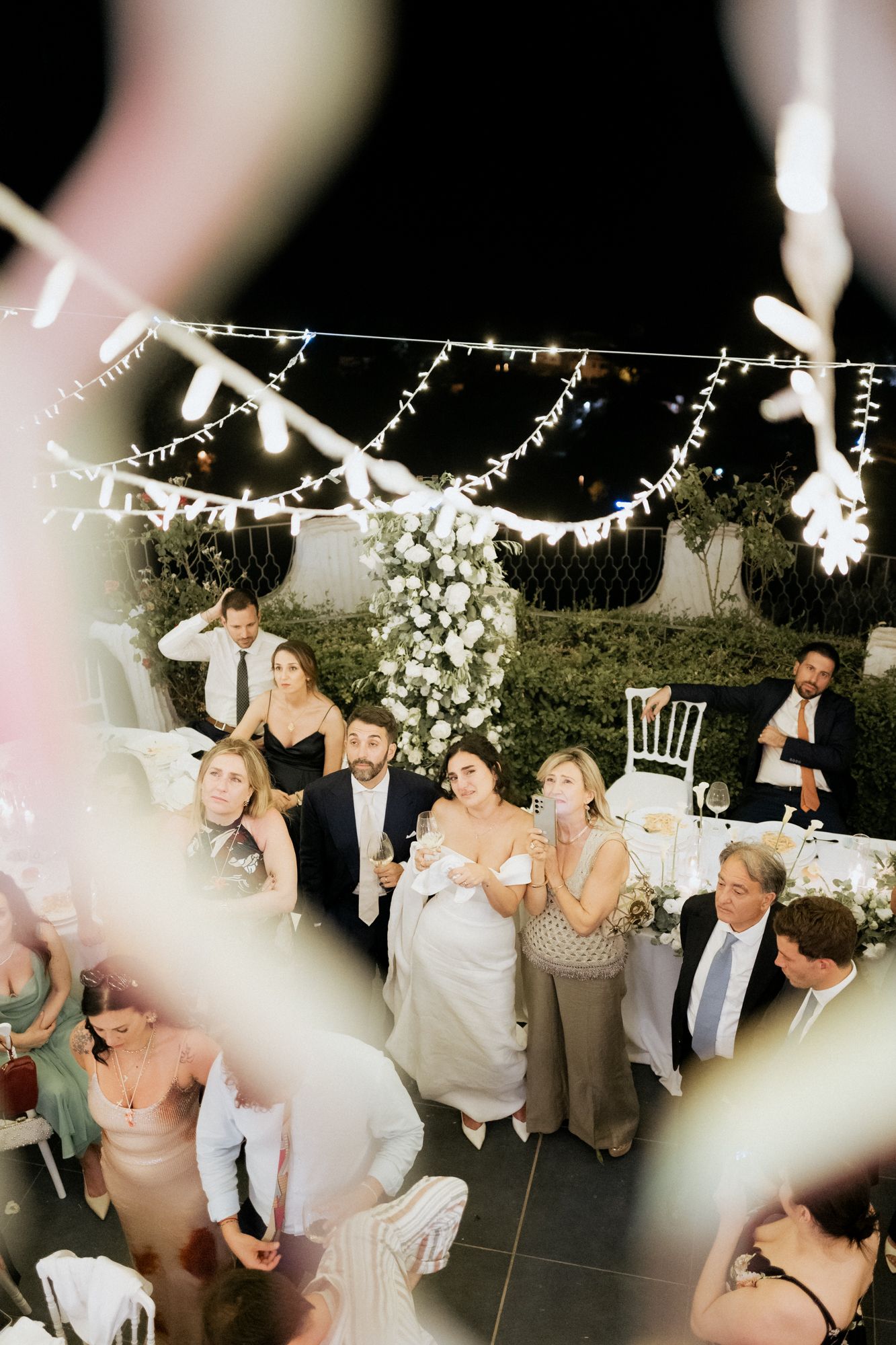 Wedding reception dance party under string lights with guests celebrating.