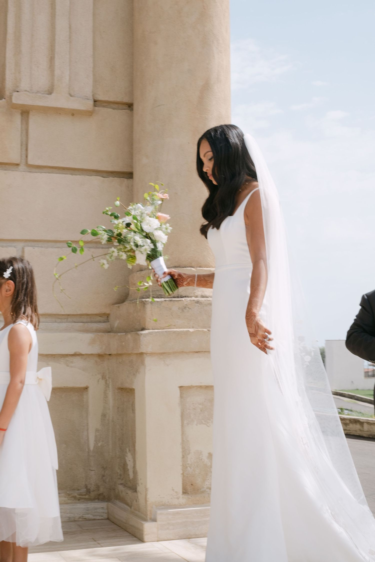 Flowing white wedding dress photographed in sequence against classical stone columns.