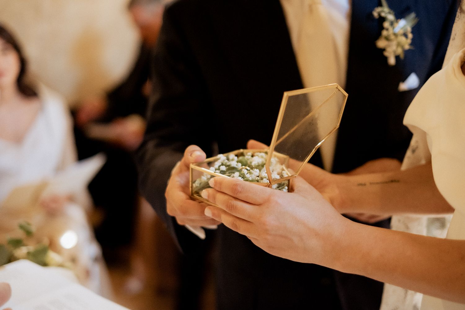 Close-up shot of hands holding a geometric glass container at a wedding celebration.