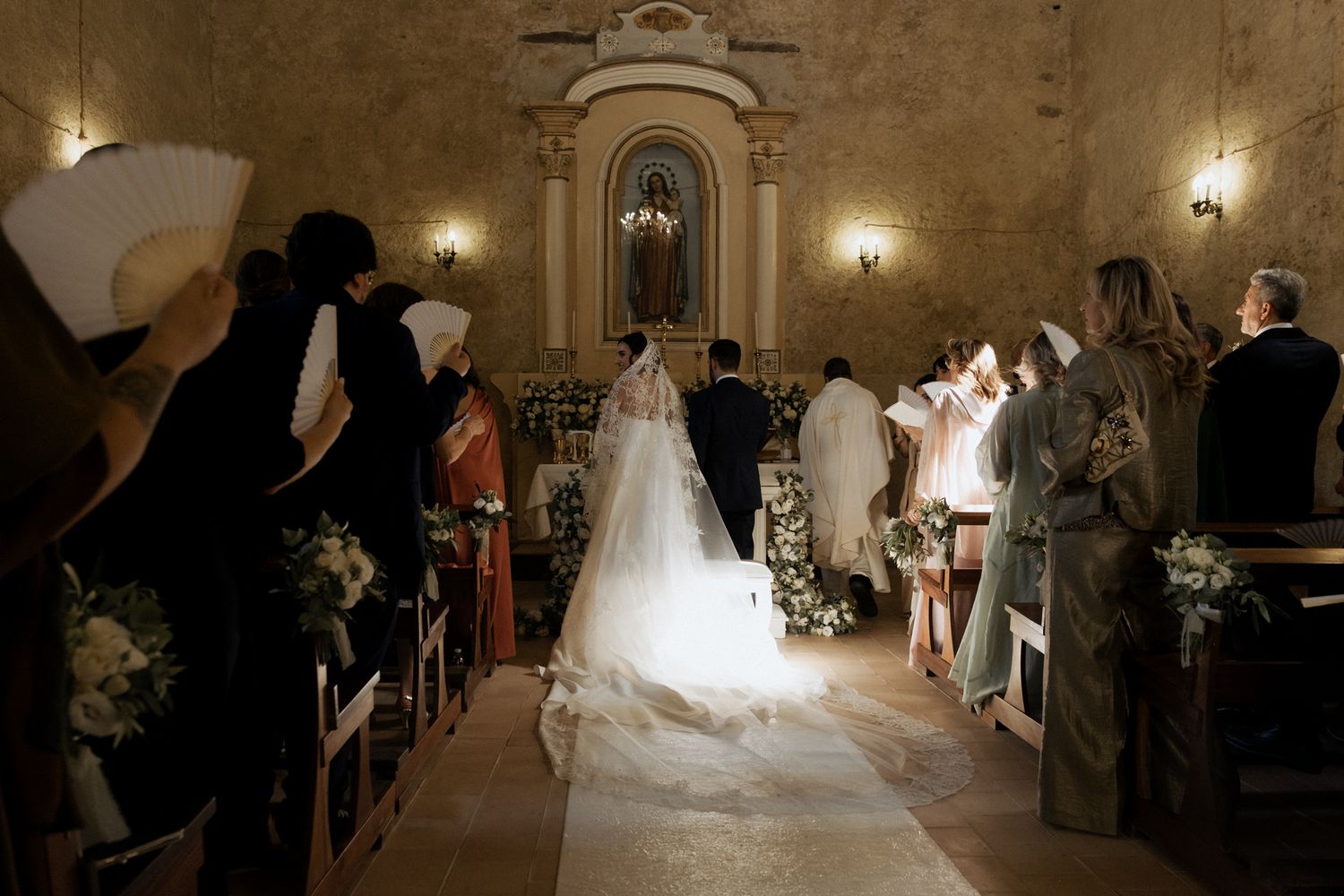 Wedding ceremony in progress inside a historic church with stone walls and elegant lighting.