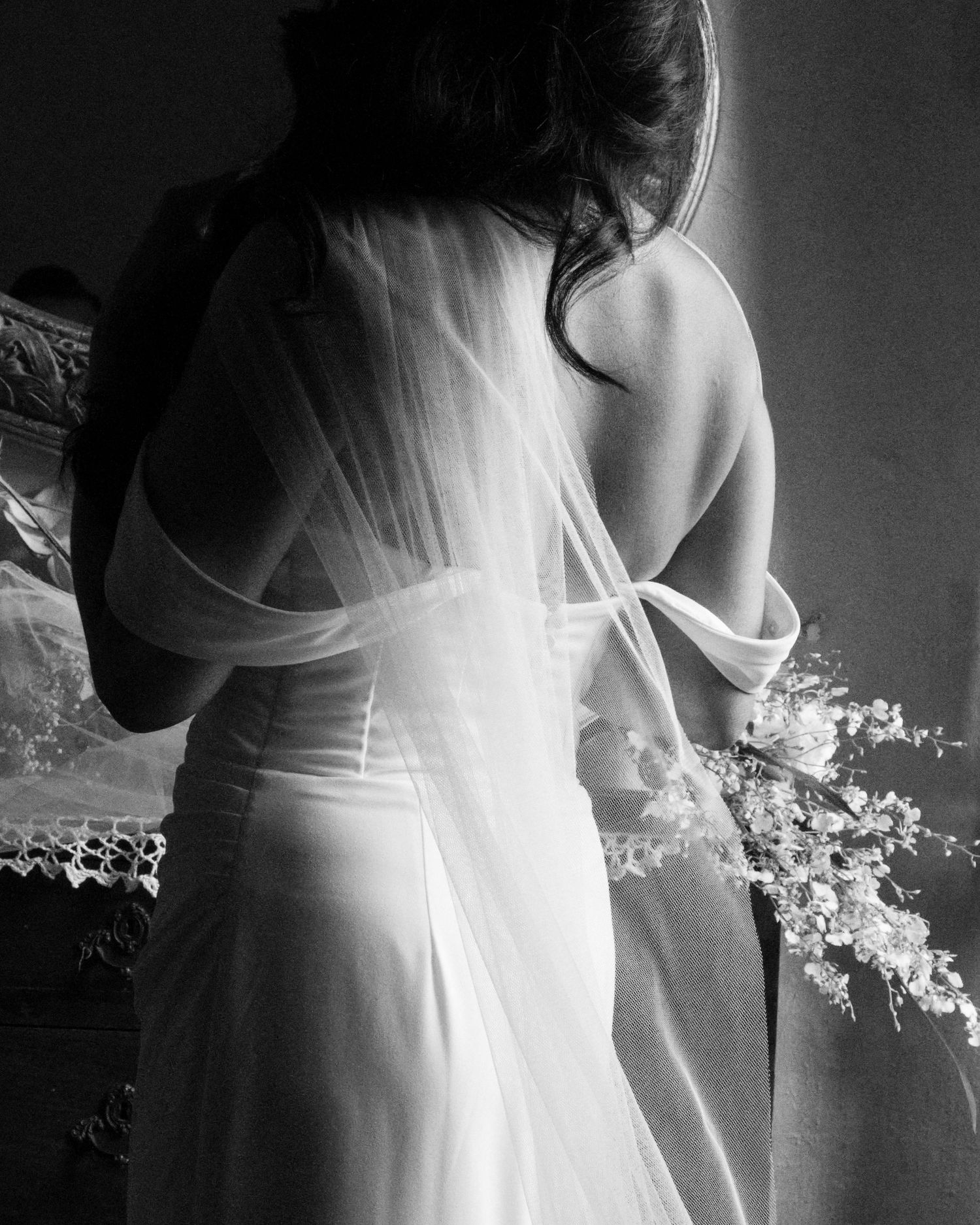A series of black and white photos showing a woman in a flowing white dress standing against a dark background.