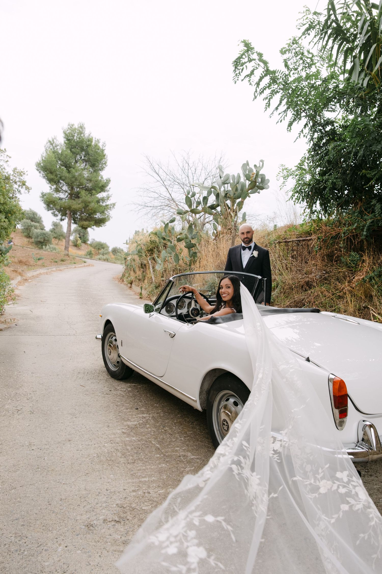 A sequence of wedding photos featuring a couple riding in a vintage white convertible car on a scenic road.
