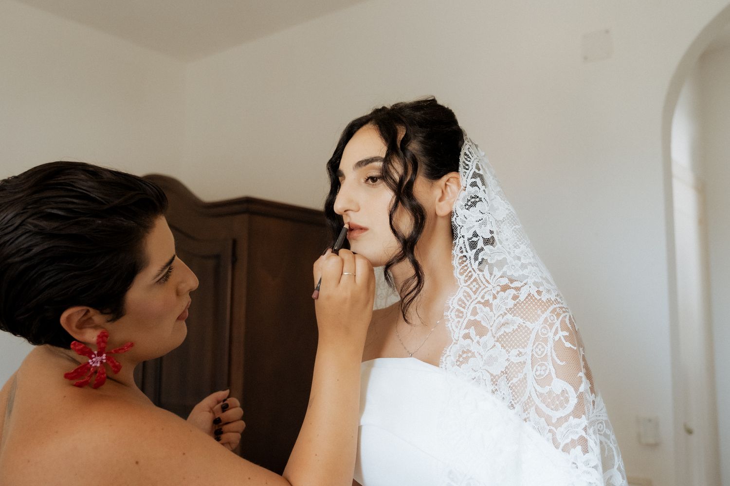 Final touches being applied to a bride's makeup on her wedding day.