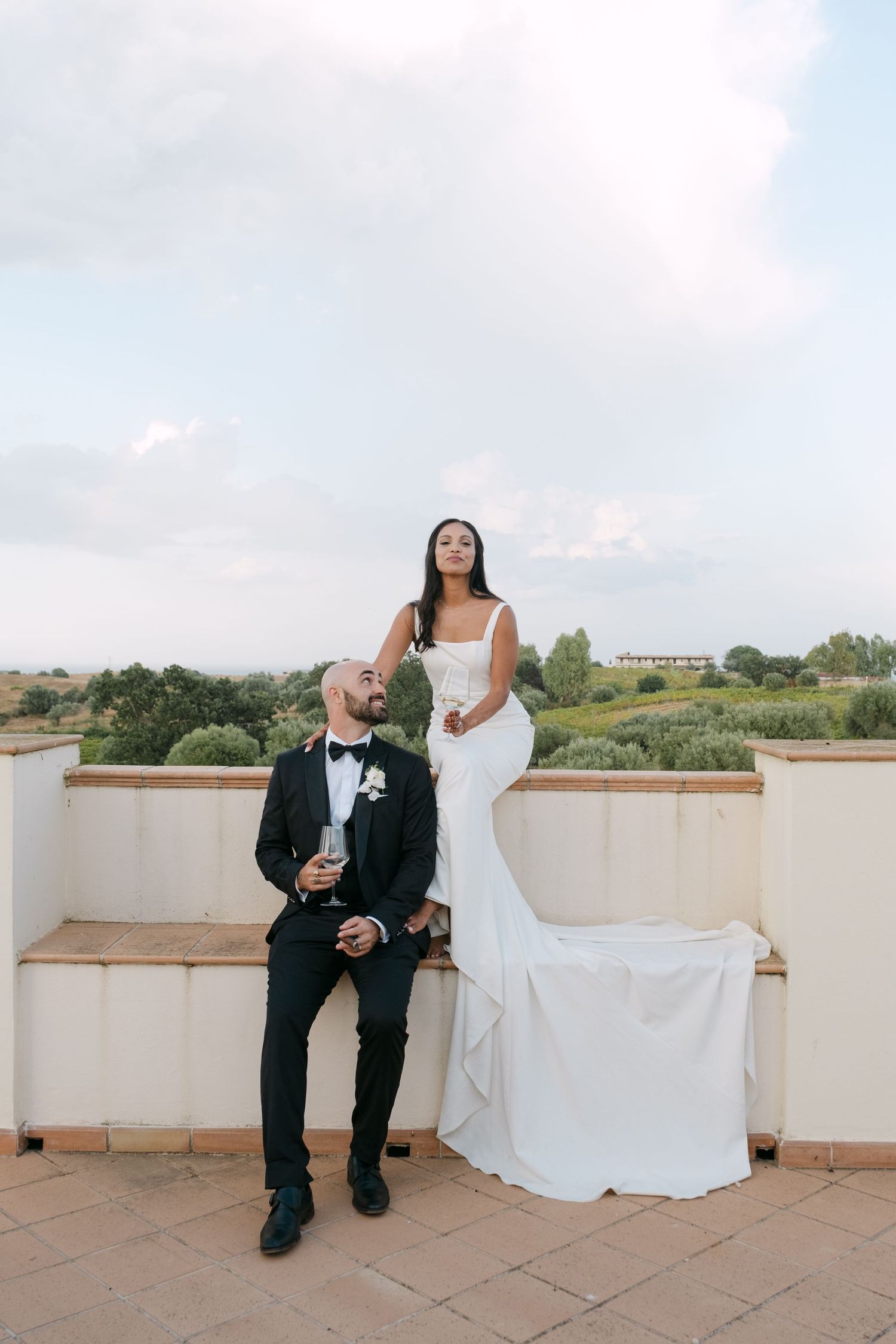 Newlyweds sitting together on a rooftop terrace during sunset.