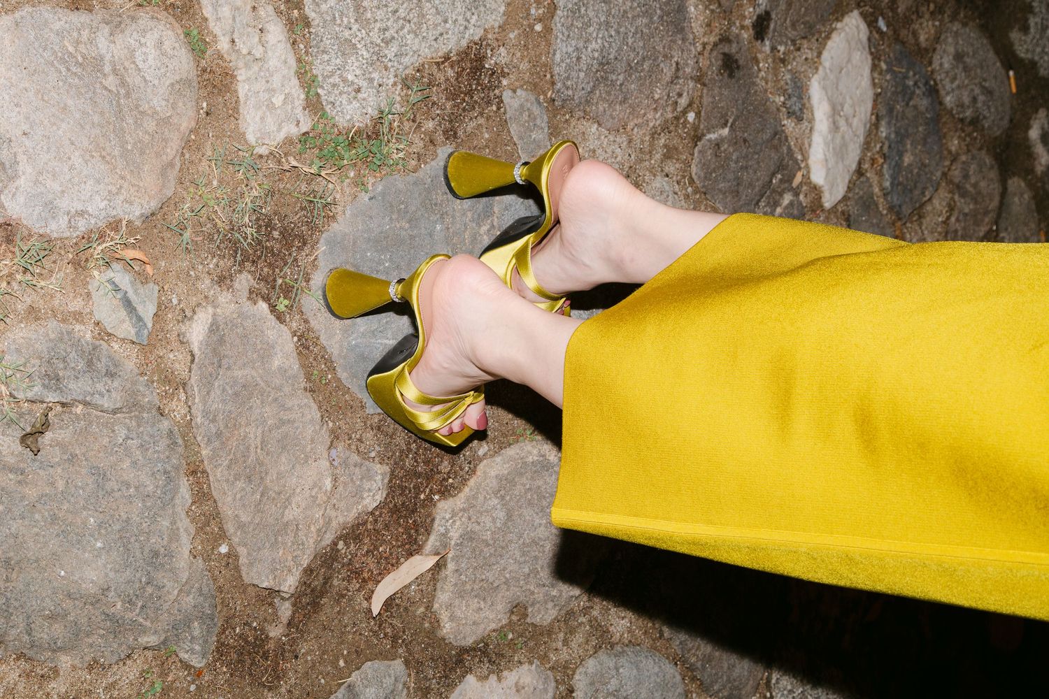 Close-up of yellow fabric against a stone wall texture.