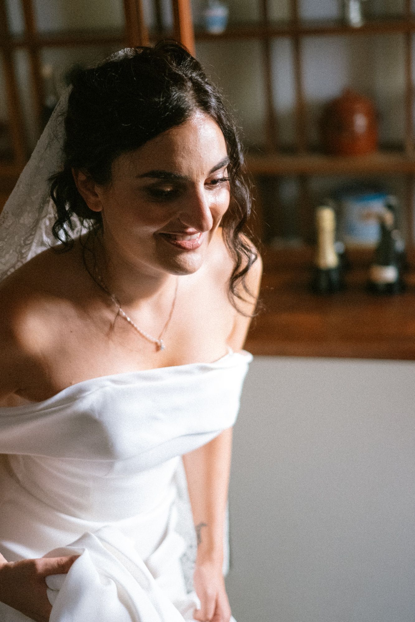 Bride in a modern white wedding gown with dramatic sleeves poses in soft natural light.