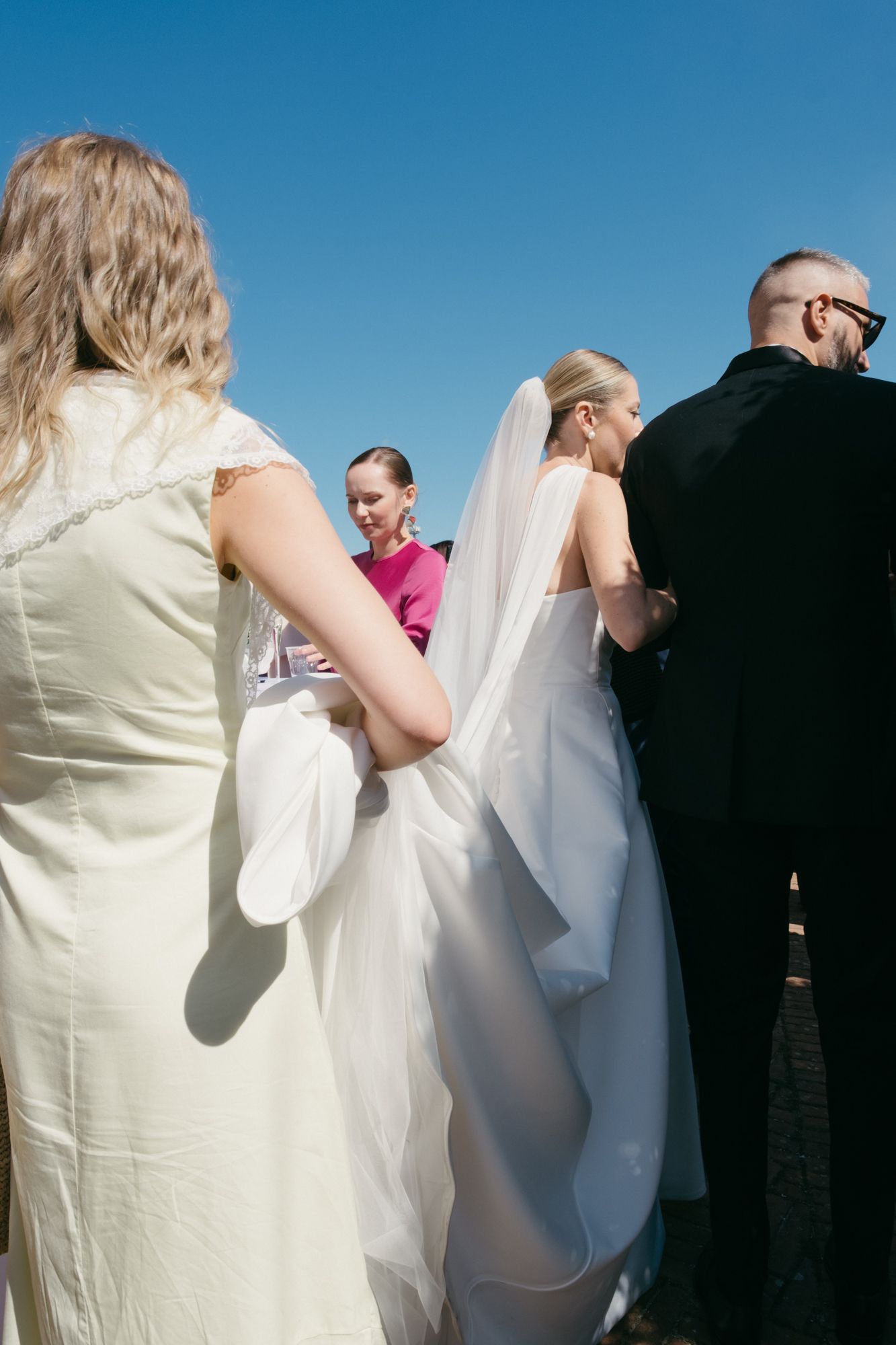 A sequence of wedding ceremony moments showing people in formal attire against a bright blue sky background.